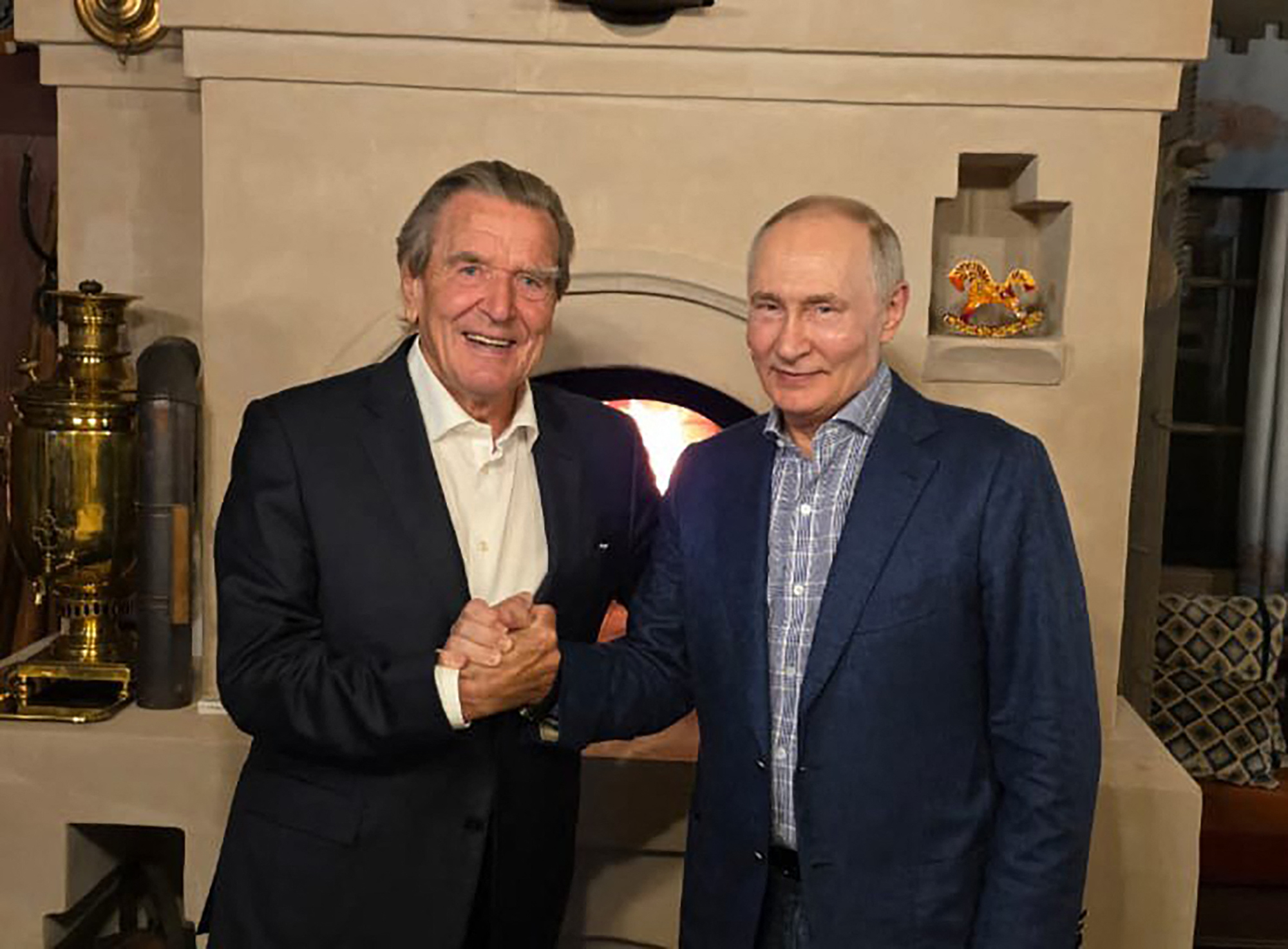 This handout photograph posted on @news_kremlin, the Telegram channel of the Russian presidential press office, on October 8, 2026, shows Russia's President Vladimir Putin and former German chancellor Gerhard Schroeder shaking hands