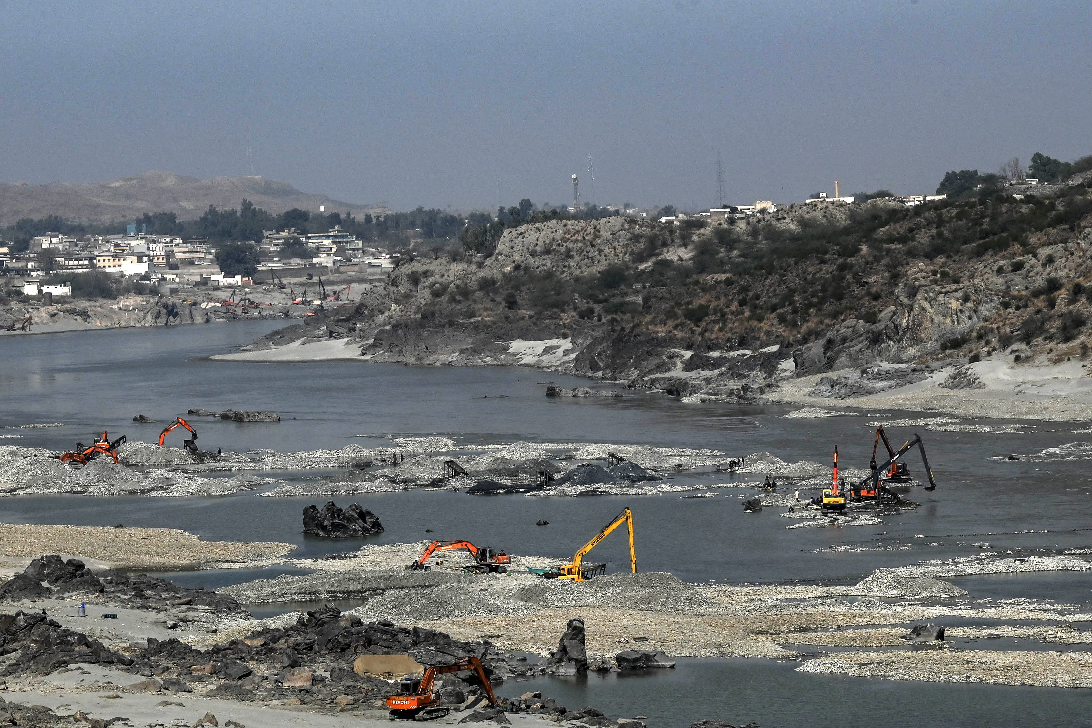 Prospectors use excavators to search for gold particles on the Kabul riverbed near Attock Bridge in Khairabad in Khyber Pakhtunkhwa province on February 8, 2025. (Photo by Abdul MAJEED / AFP)