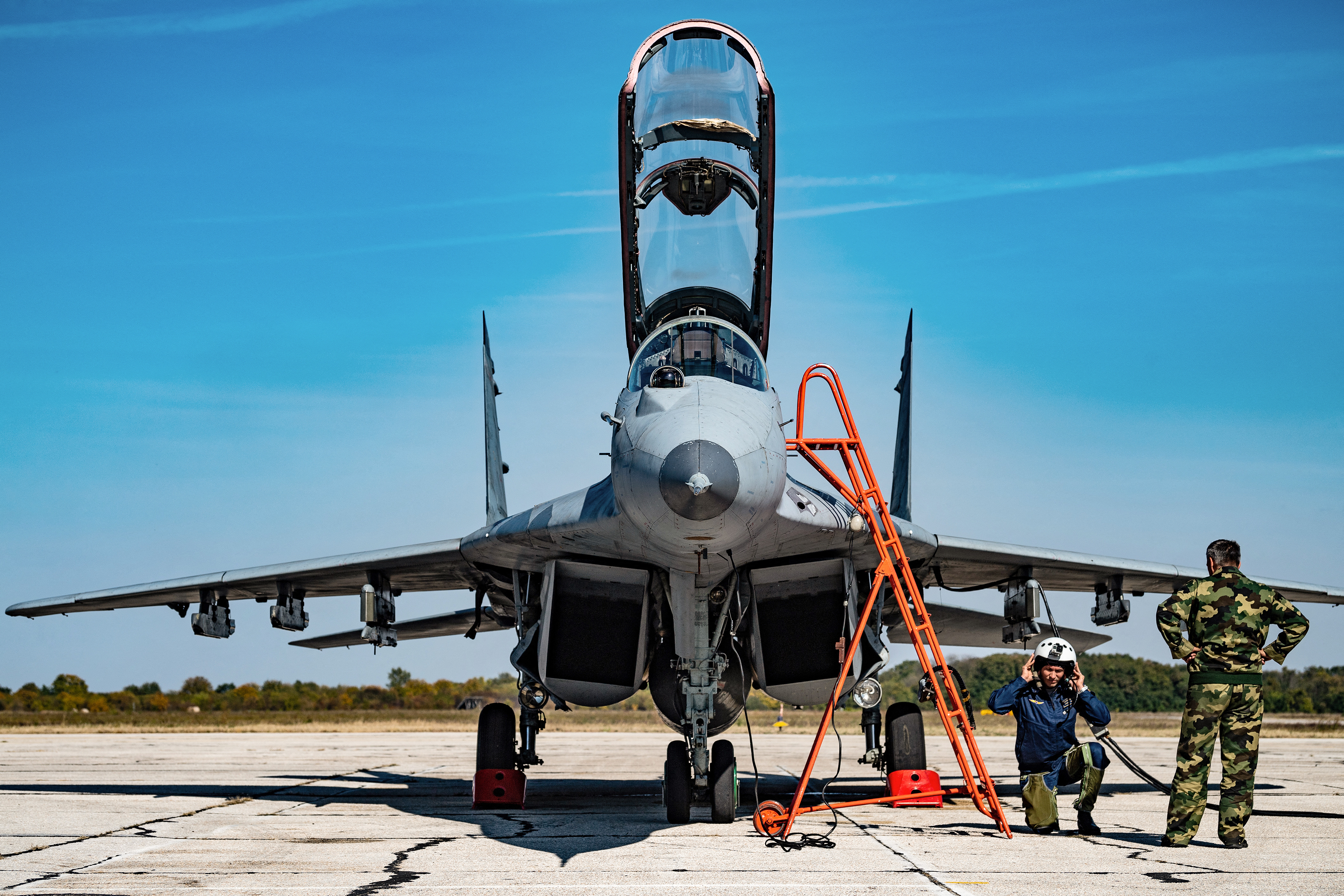 A Russian pilot (2R) prepares to board a Serbian Air Force Mig 29 fighter plane. (Photo by ANDREJ ISAKOVIC / AFP)