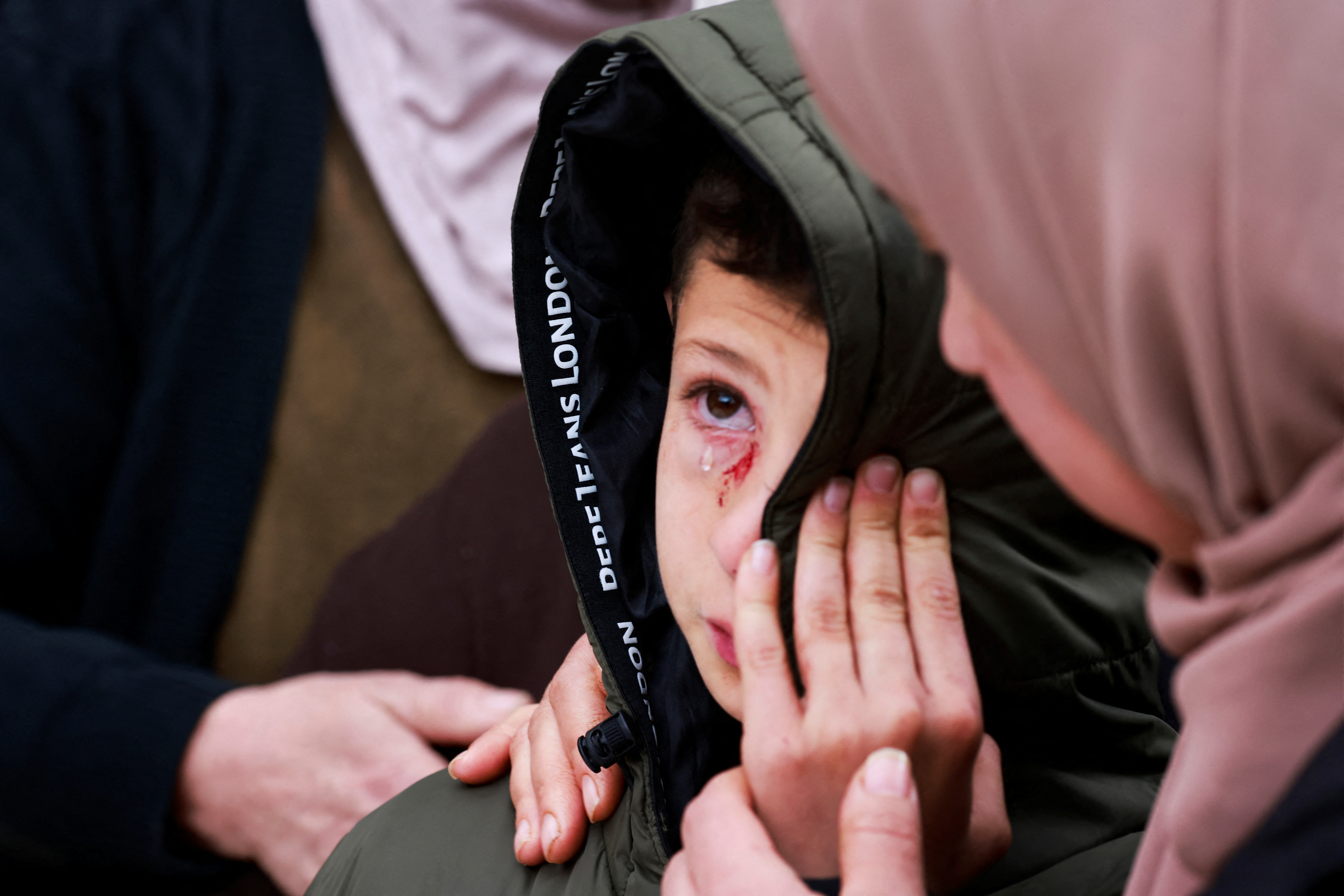 Mustafa, who was injured but survived after Israeli soldiers fired on the vehicle carrying his parents and two siblings, is comforted during the funeral of his family in the Israeli-occupied West Bank’s