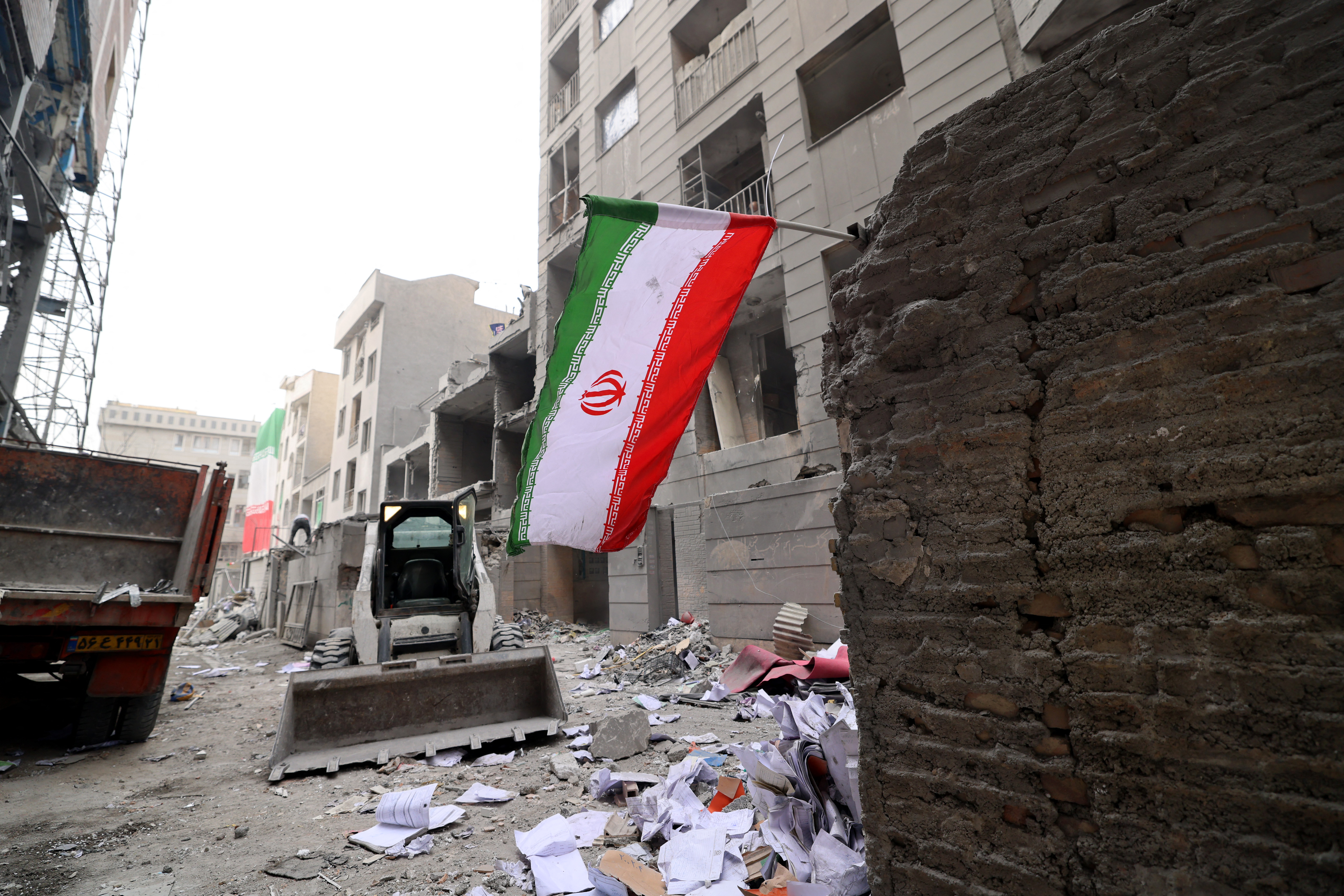 An Iranian flag flutters as as digger arrives to help remove the debris. (Photo by Atta KENARE / AFP) /