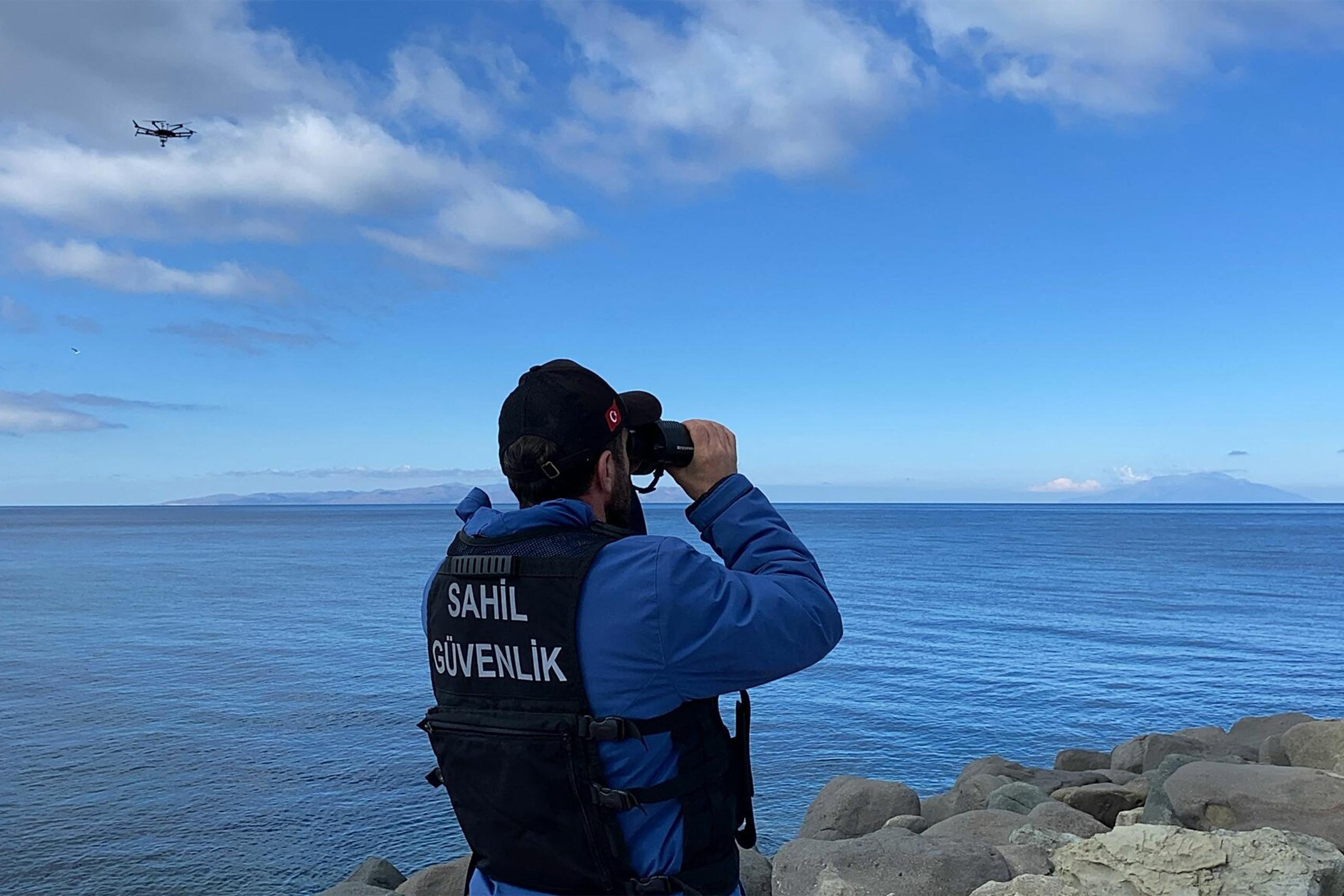 oast guard officer looking through binoculars as a drone searches for victims, after at least eight migrants drowned after a boat carrying them capsized off the Turkish coast. AFP PHOTO / DHA (DEMIROREN NEWS AGENCY)