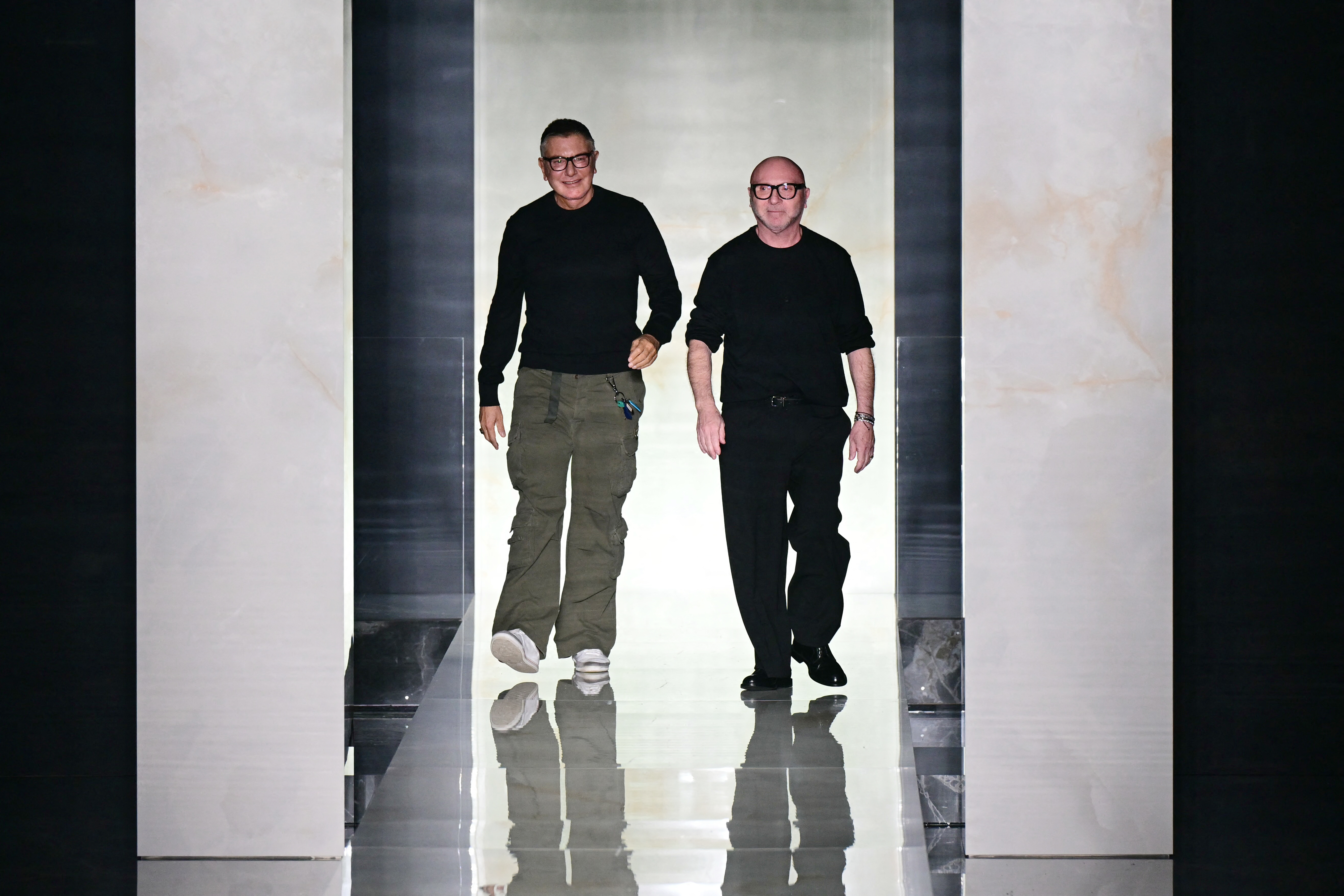 Italian designers Stefano Gabbana and Domenico Dolce (R) greet the audience at the end of the Dolce & Gabbana collection show at Milan's fashion week for the Men's Fall/Winter 2026-2027, on January 17, 2026 in Milan. (Photo by Stefano RELLANDINI / AFP)