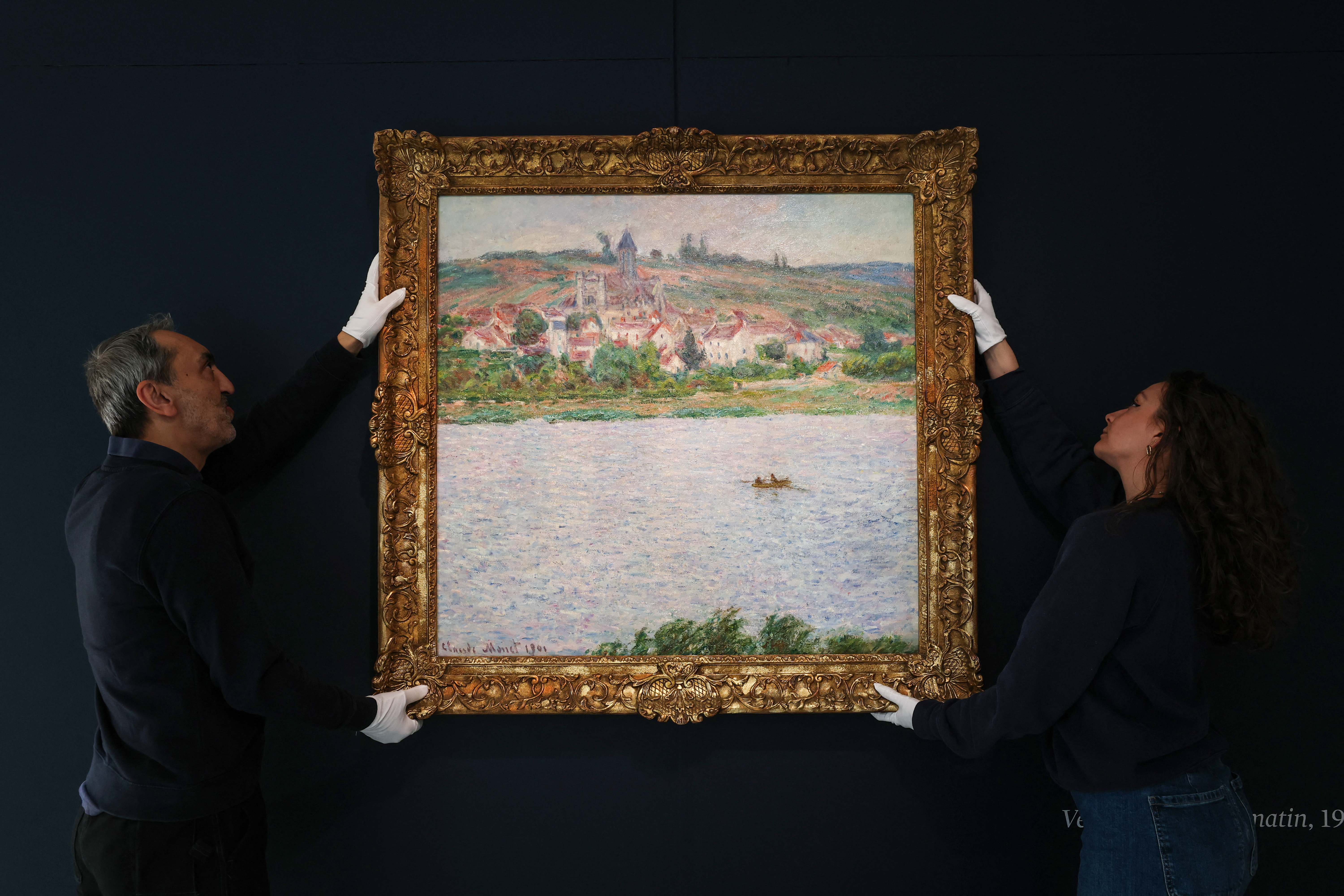 Employees of the Sotheby's auction house handle the painting "Vétheuil, Effet du Matin. (Photo by Anne-Christine POUJOULAT / AFP)