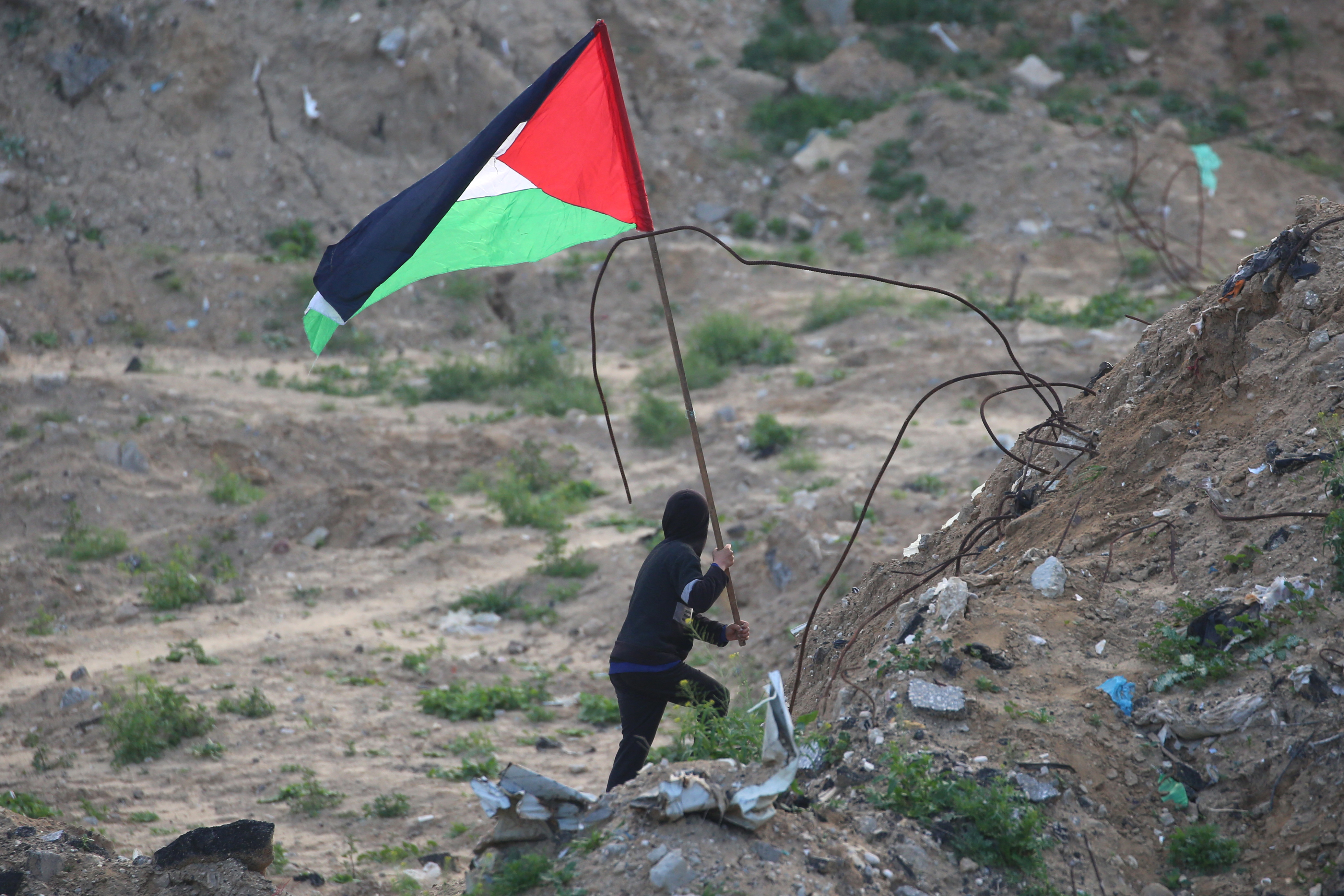 A Palestinian youth waves the flag of Palestine at the site of the handing over of the bodies of four Israeli hostages in Khan Yunis in the southern Gaza on February 20, 2025.