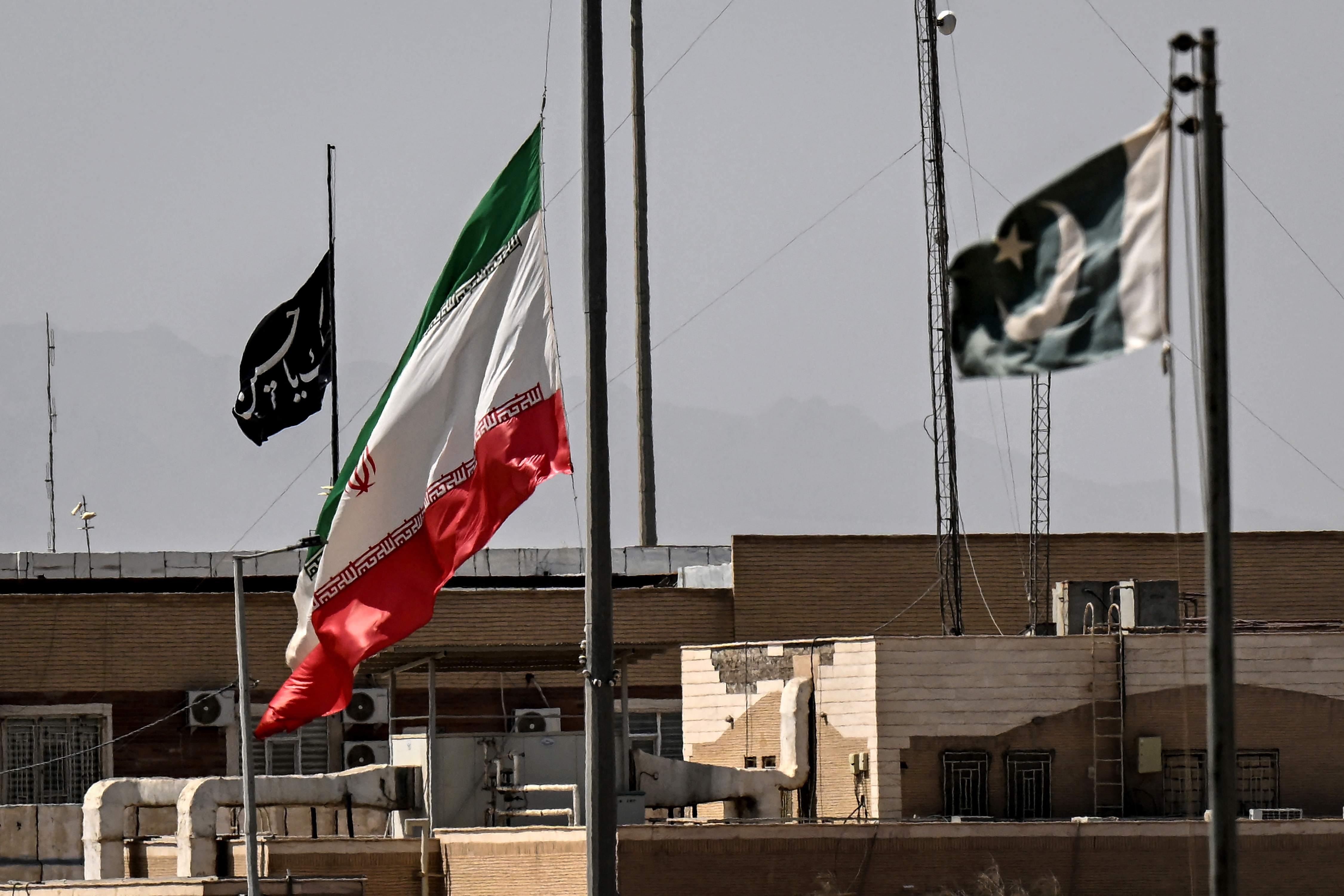 An Iranian flag (C) flies at half-mast at the Pakistan-Iran border. (Photo by Banaras KHAN / AFP)