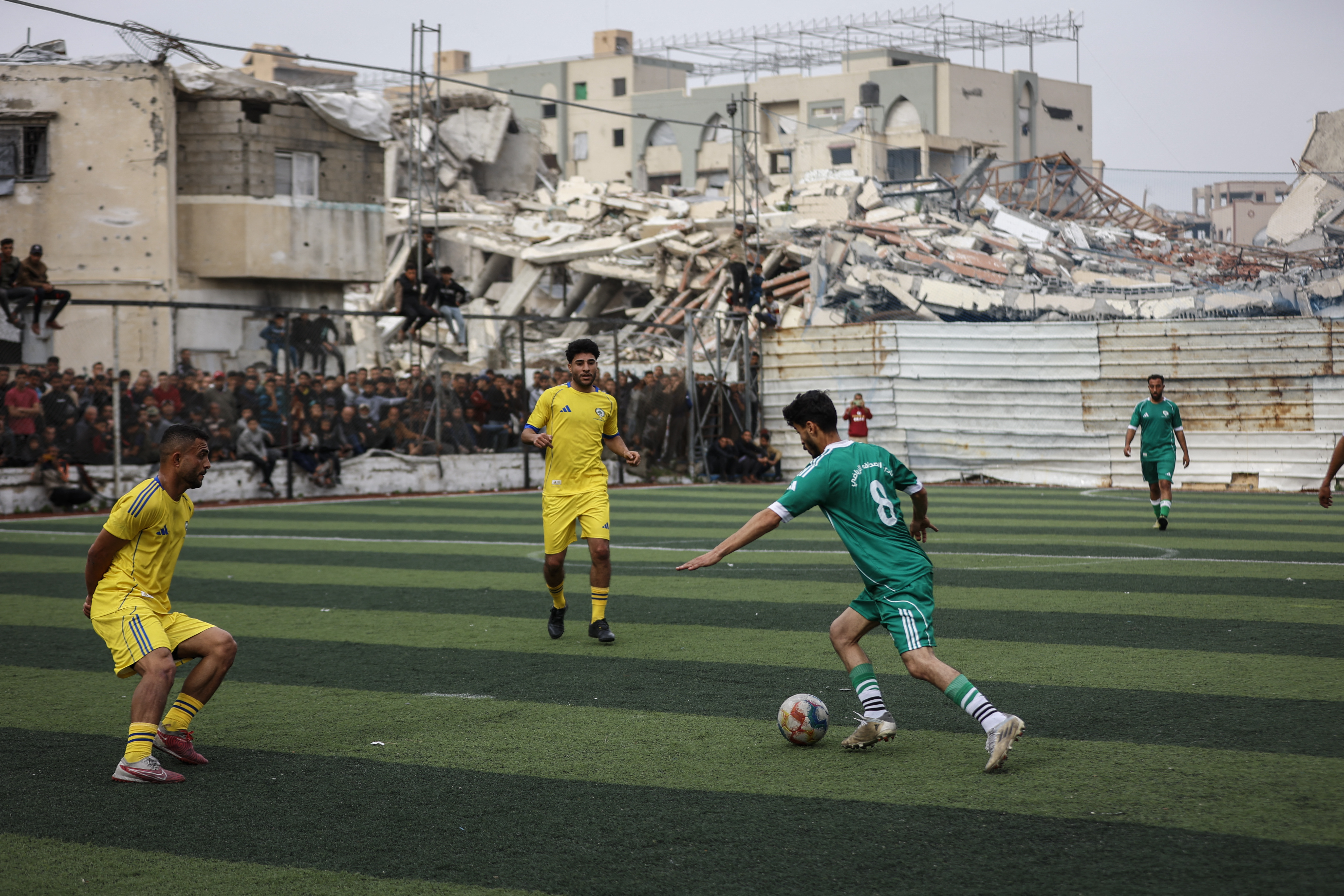 Palestinians watch a five-a-side football match amid the rubble of destroyed buildings in Gaza City on February 9, 2026.