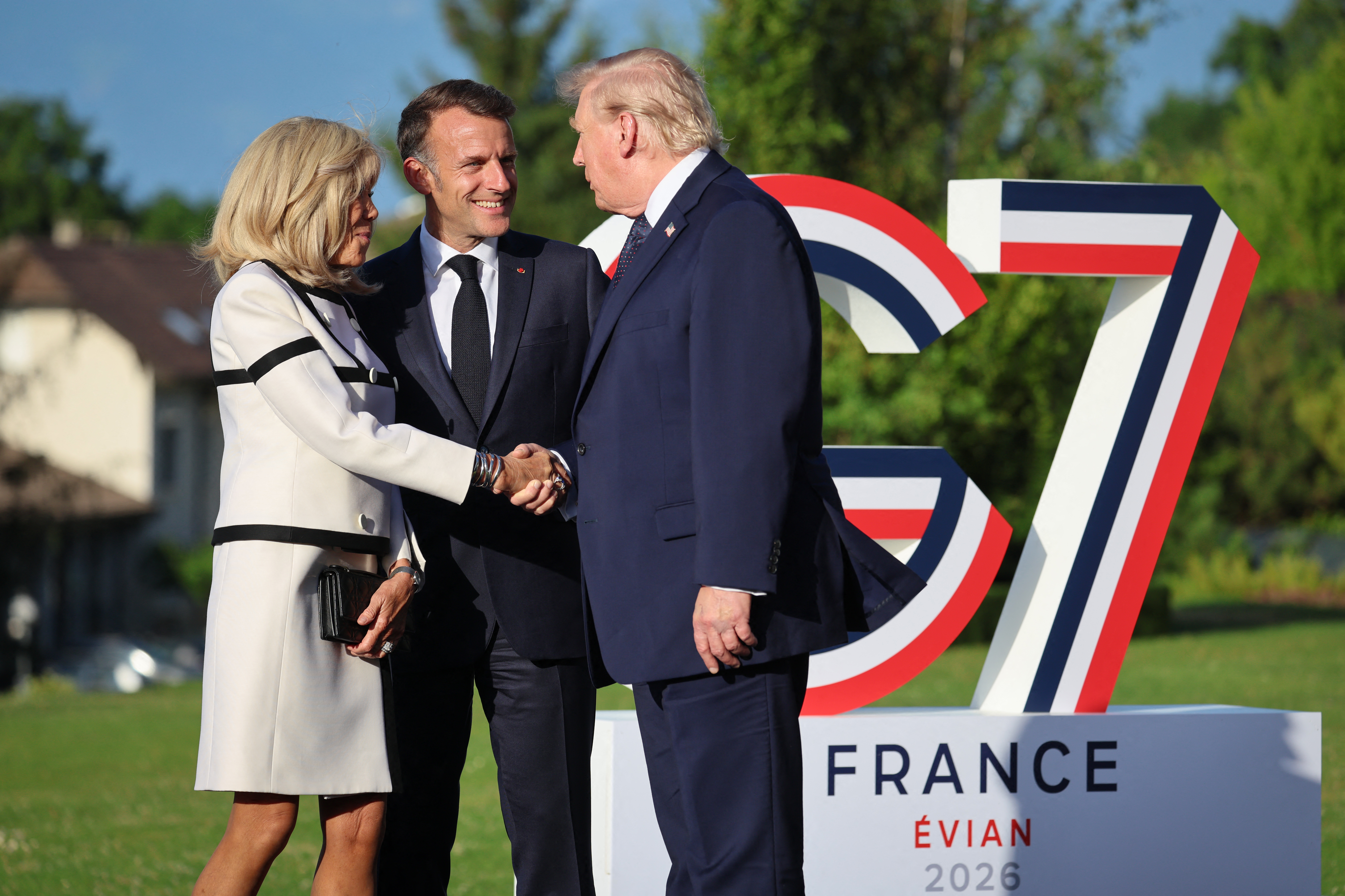 France's President Emmanuel Macron (C) and his wife Brigitte Macron (L) greet US President Donald Trump during the G7 summit, in Evian, eastern France, on June 15, 2026.