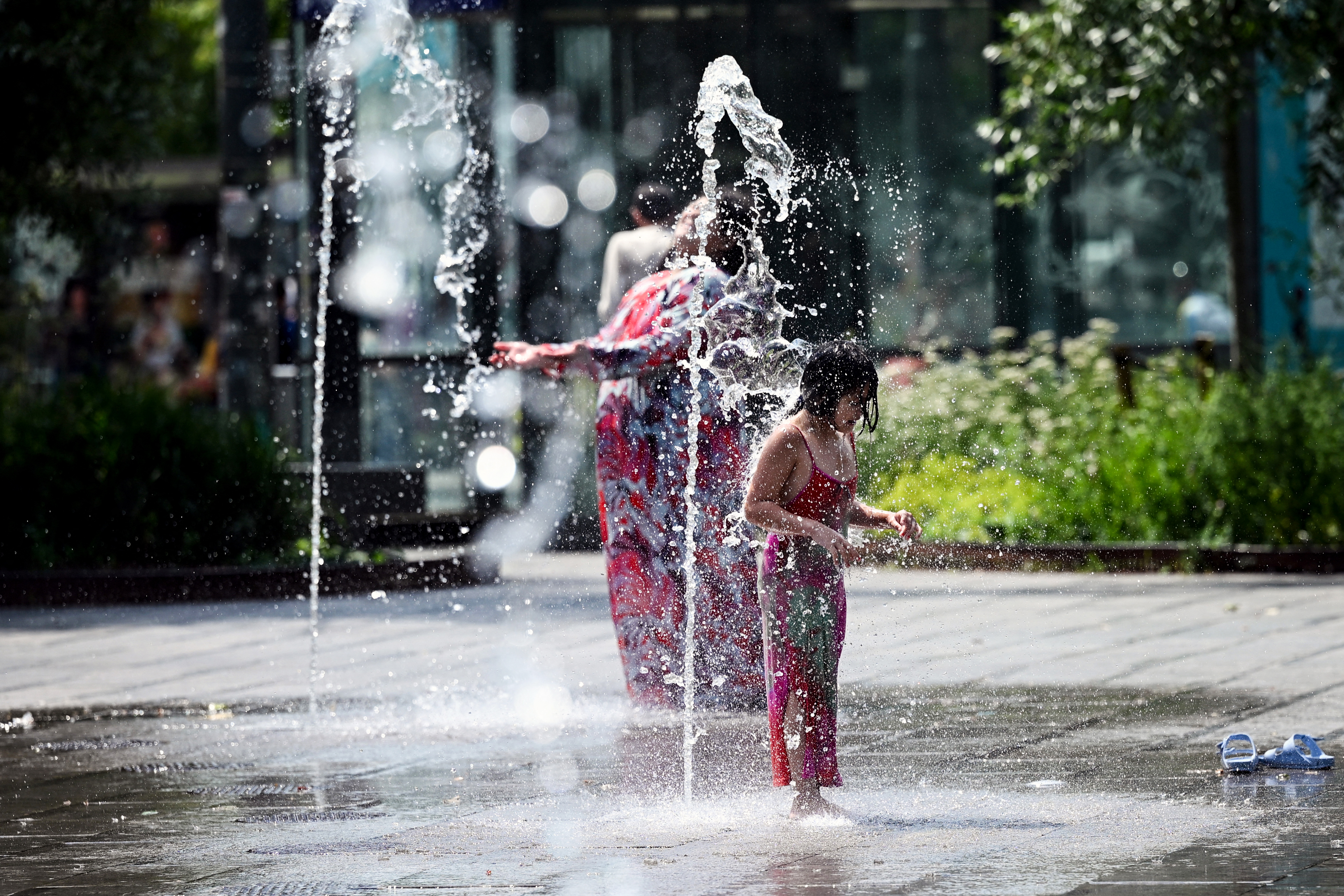 A child cools off under a water sprays, in Brussels, during a heatwave on June 19, 2026. (Photo by Nicolas TUCAT / AFP)