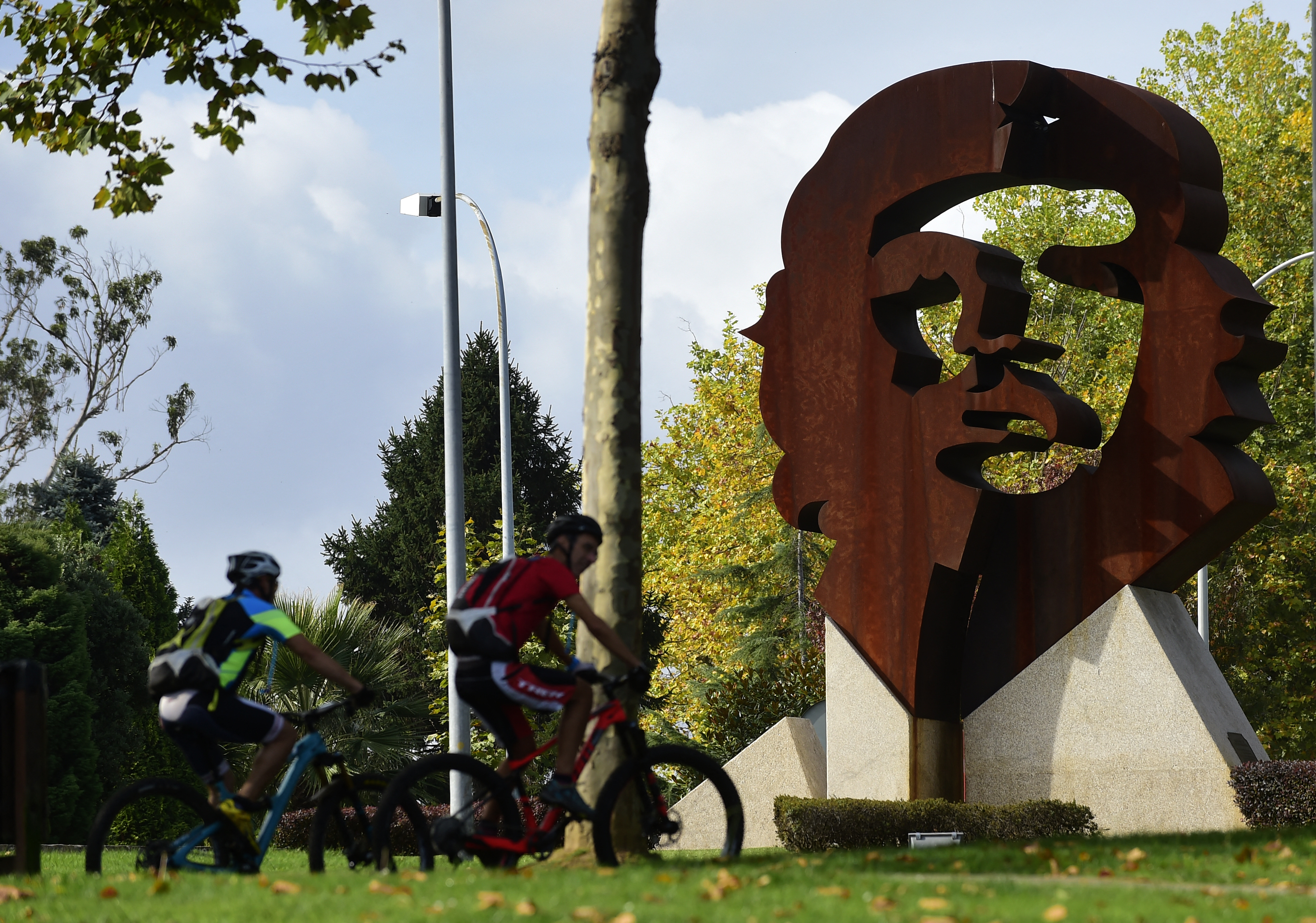 Two people ride bikes past a monument dipicting the image of late Argentinian revolutionary legend Ernesto "Che" Guevara, in Oleiros, some 10 km from Coruna, northwestern Spain, on September 29, 2017.