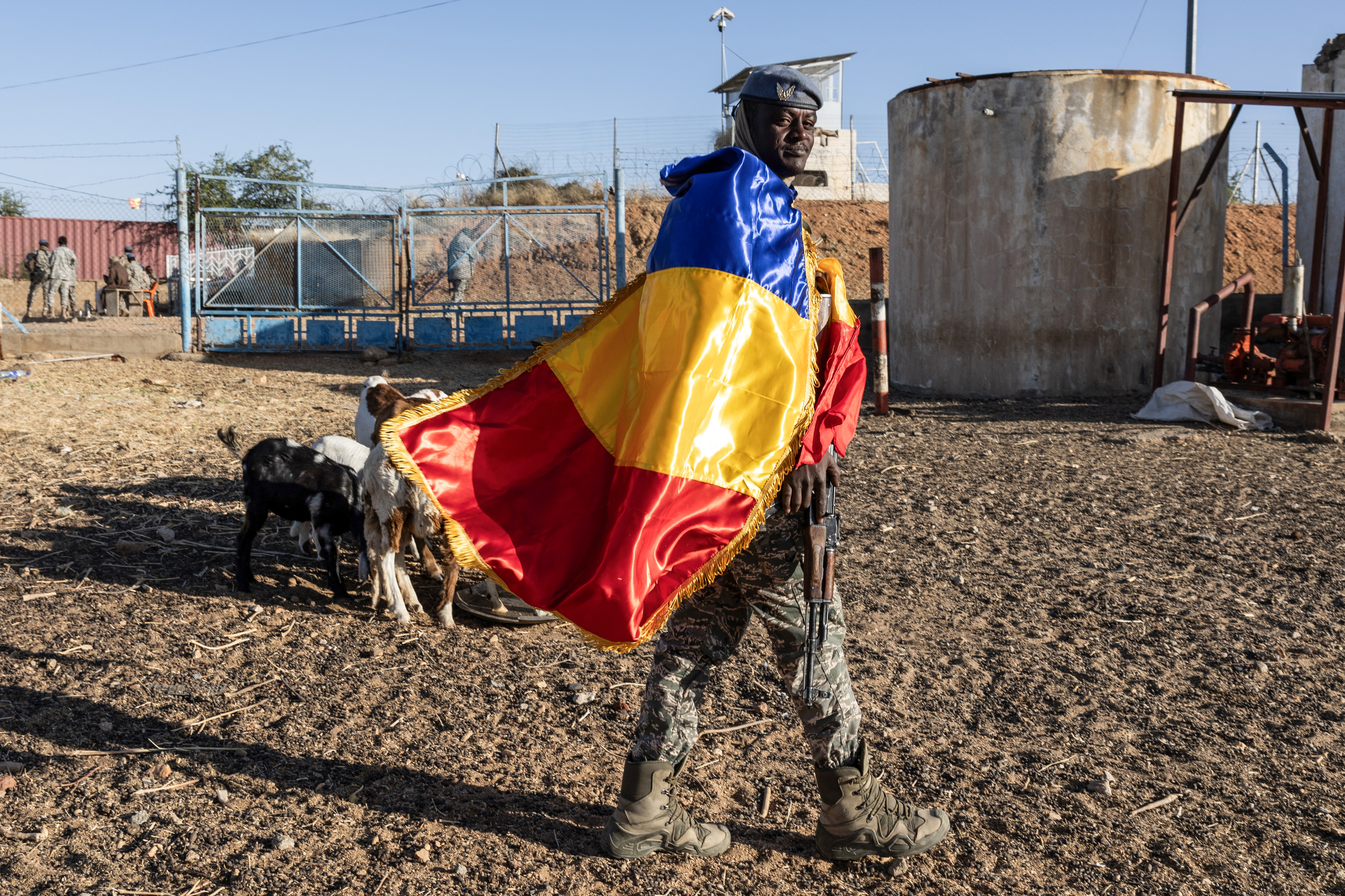 A Chadian soldier draped in the national flag monitors the area in front of the French military base in Abeche on January 11, 2025, ahead of the departure of French soldiers from Abeche base. (Photo by Joris Bolomey / AFP)