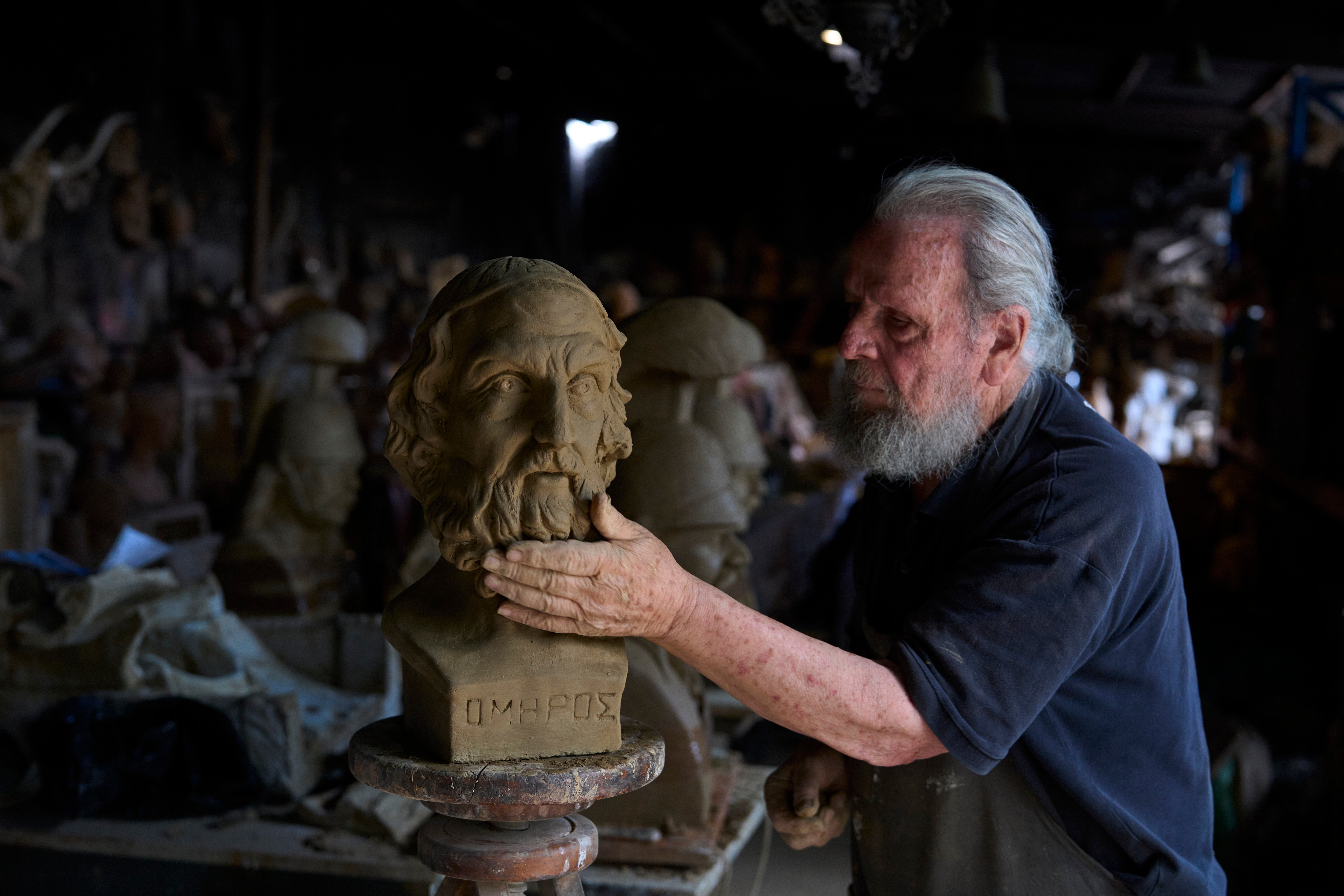 Sculptor and ceramicist Haralambos Goumas works on a terracotta bust of the ancient Greek poet Homer. (AP Photo/Petros Giannakouris)