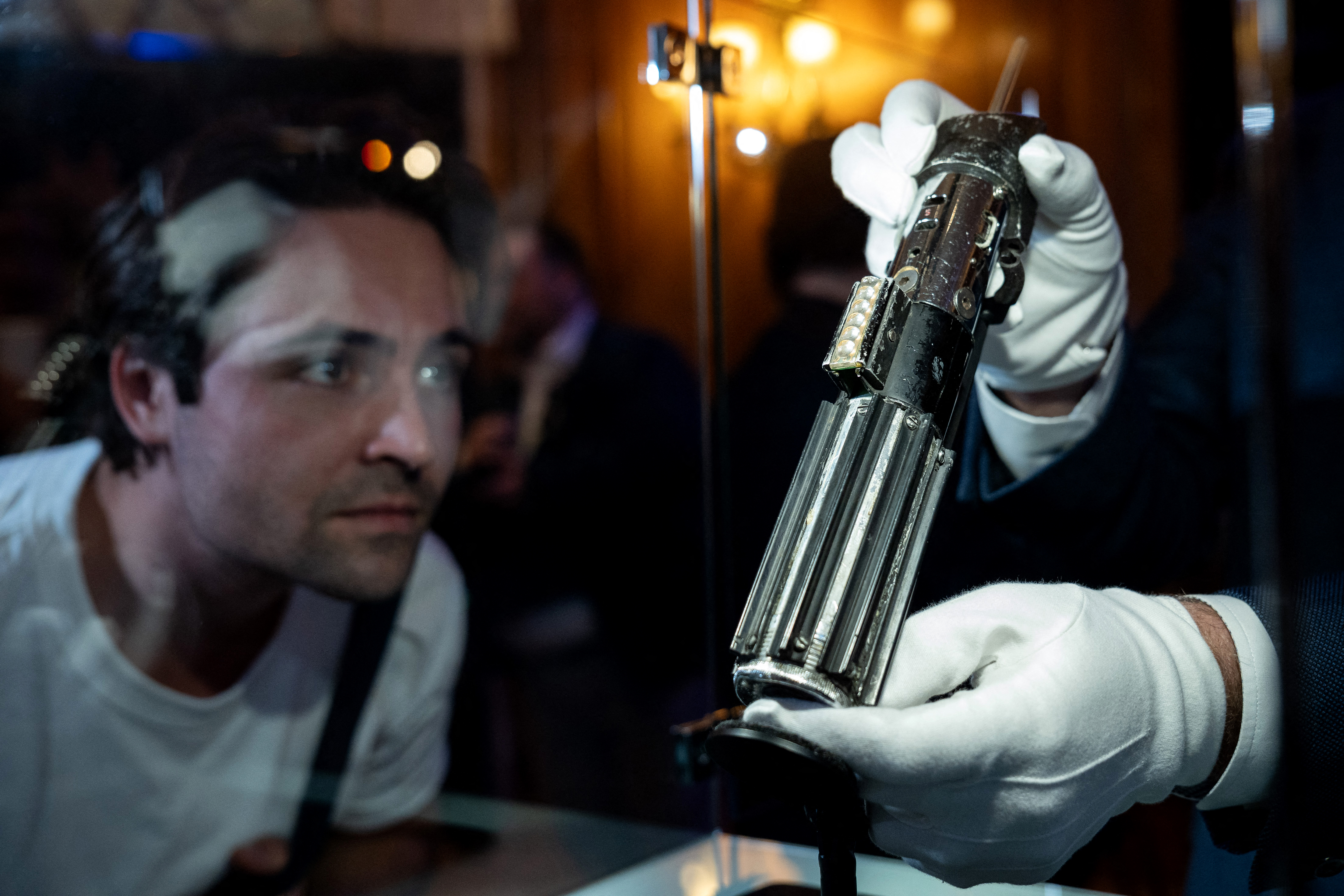 A person looks at the Lightsaber of the character Darth Vader from the films Star Wars: Empire Strikes Back and Return of the Jedi during a press preview of movie props set to go to auction, in London on August 6, 2025.