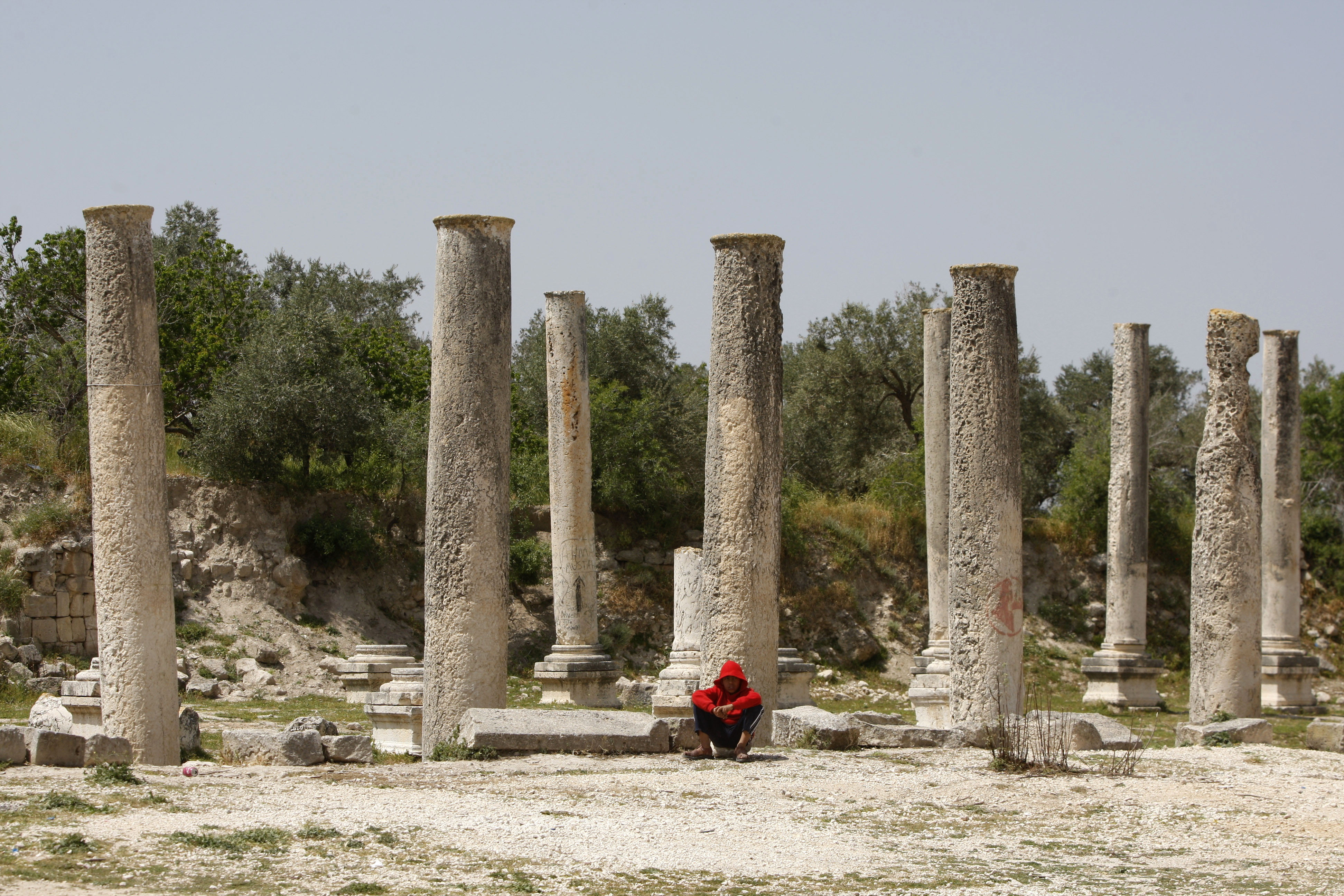 In this Saturday, April 6, 2013 photo, a Palestinian youth sits near the Roman basilica. (AP Photo/Majdi Mohammed)