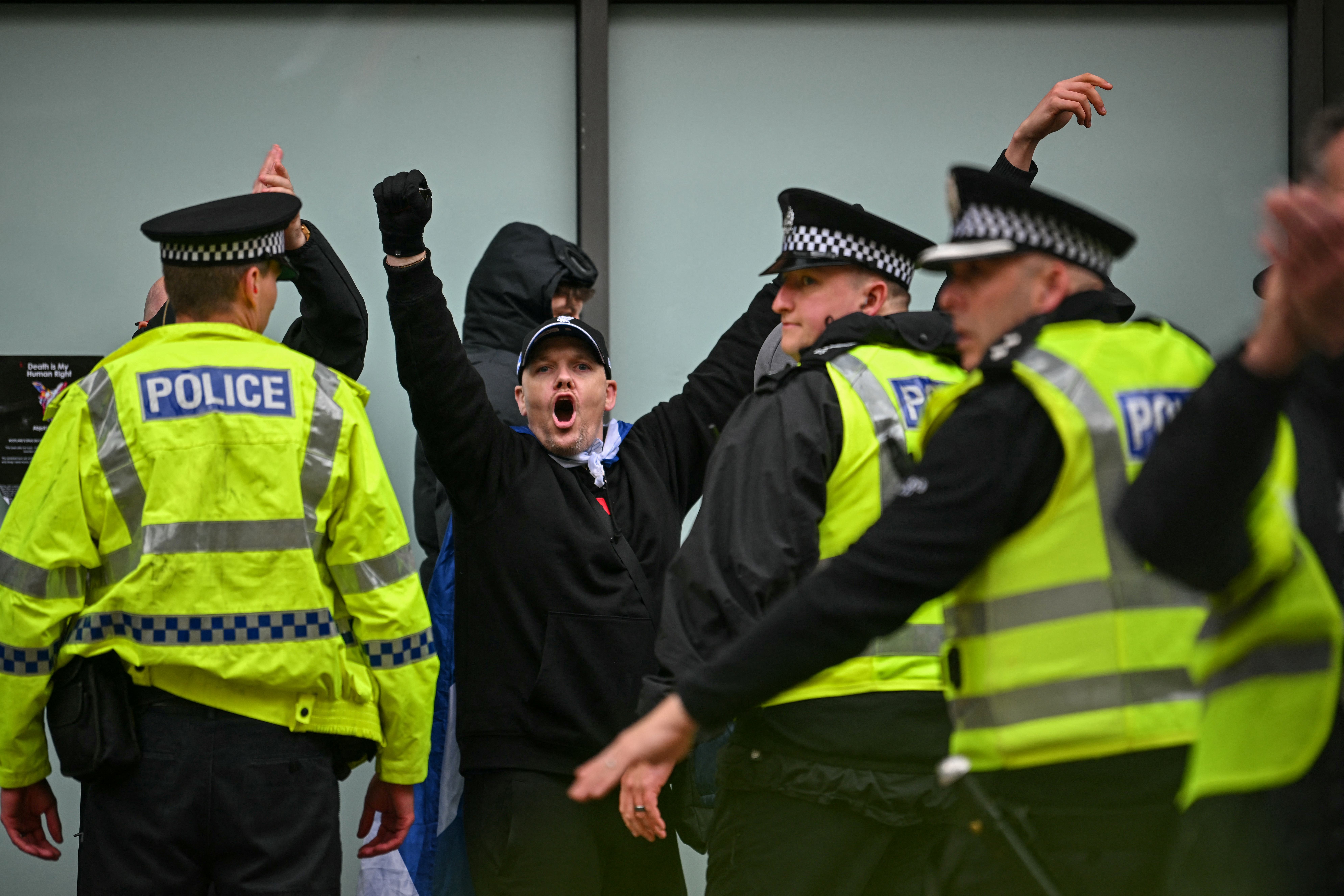 Counter-protesters are removed from the area by police as a larger group of anti-racism demonstrators hold a rally in central Glasgow, Scotland on June 13, 2026. (Photo by ANDY BUCHANAN / AFP)