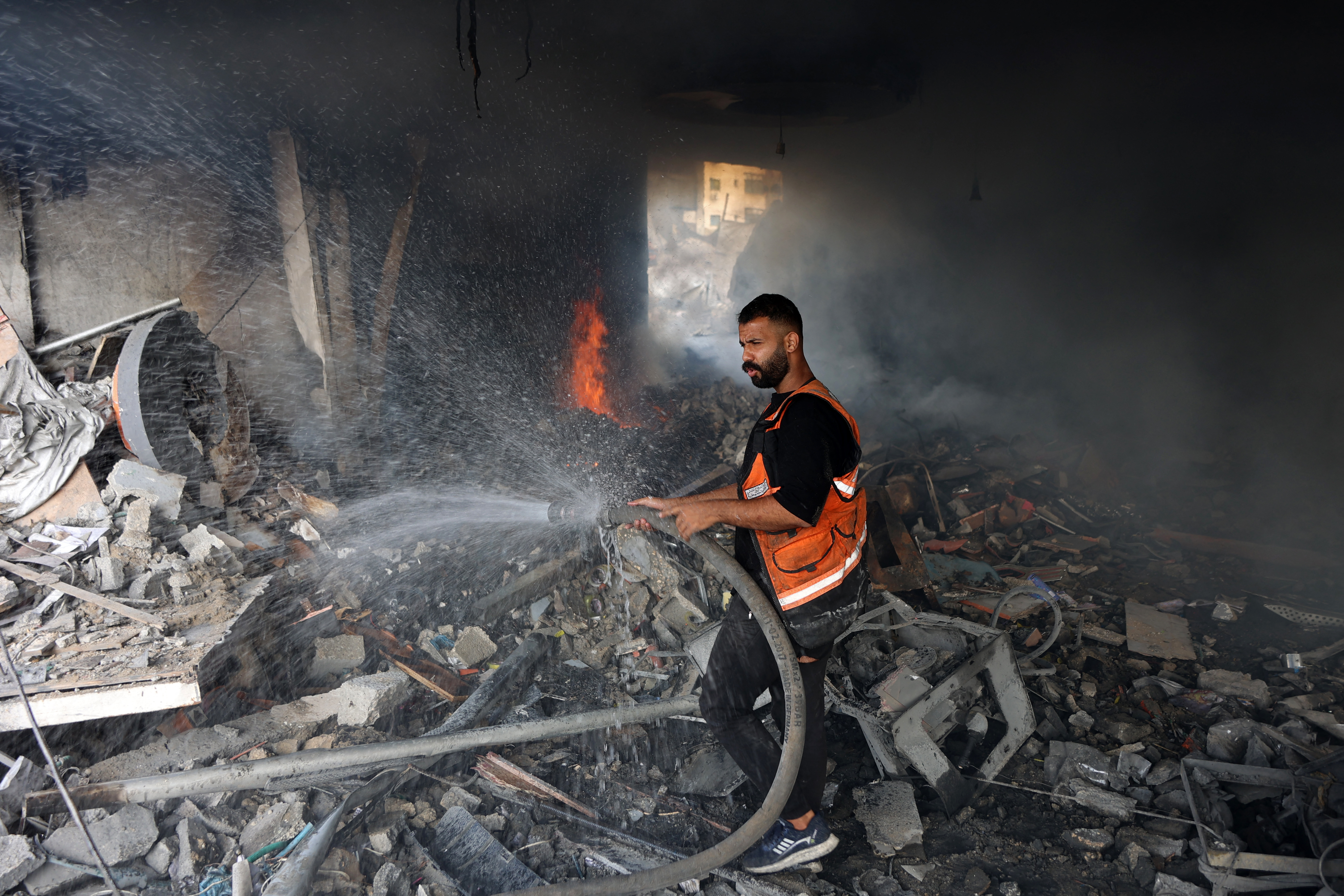 Graphic content / A firefighter tries to extinguish a fire from a destroyed building following an Israeli strike at the Al-Jalaa street in Gaza City on July 24, 2026.
