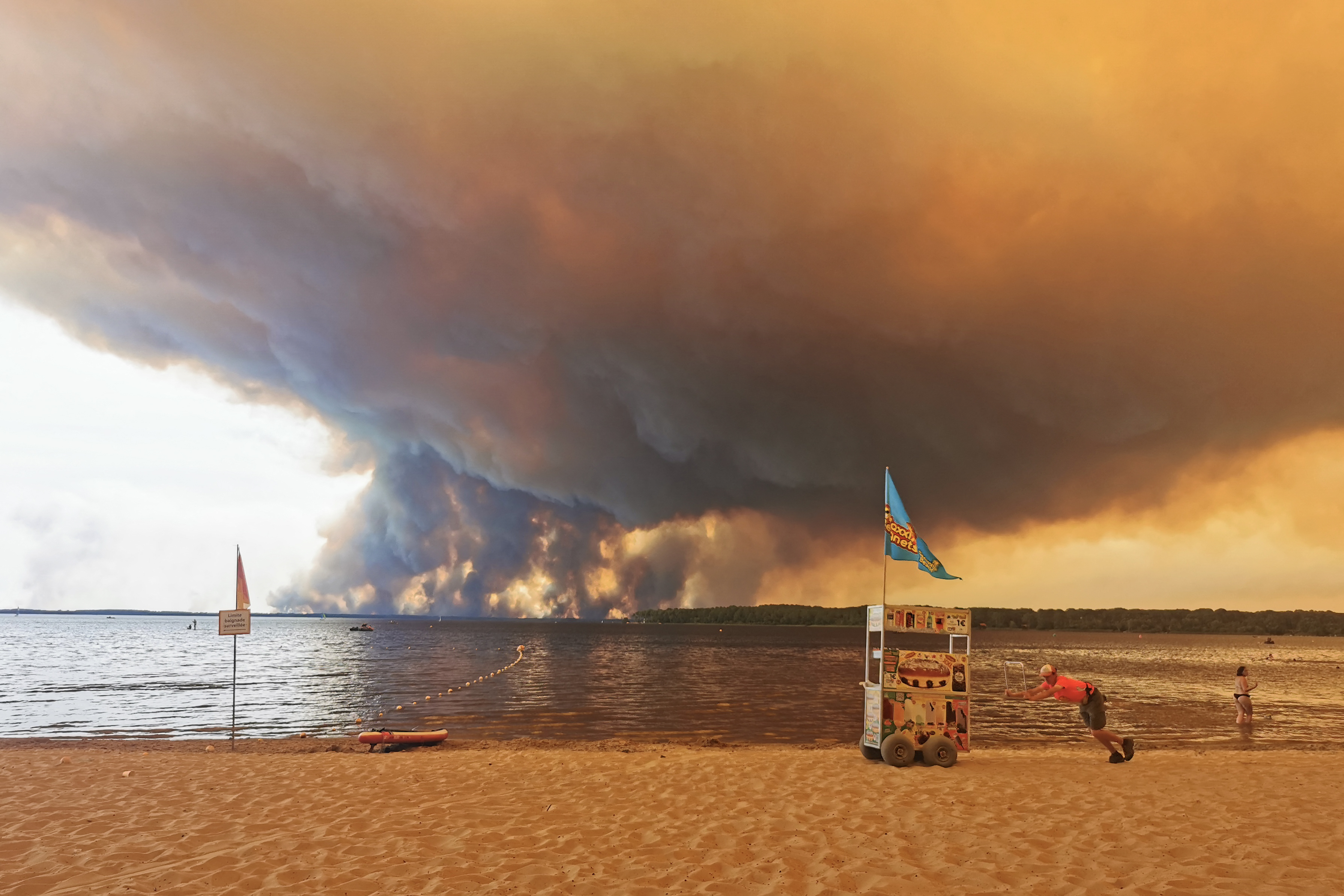 A vendor pushes a cart on the beach of Moutchic on the shore of Lake Lacanau. (Photo by Maximilien LAMY / AFP)