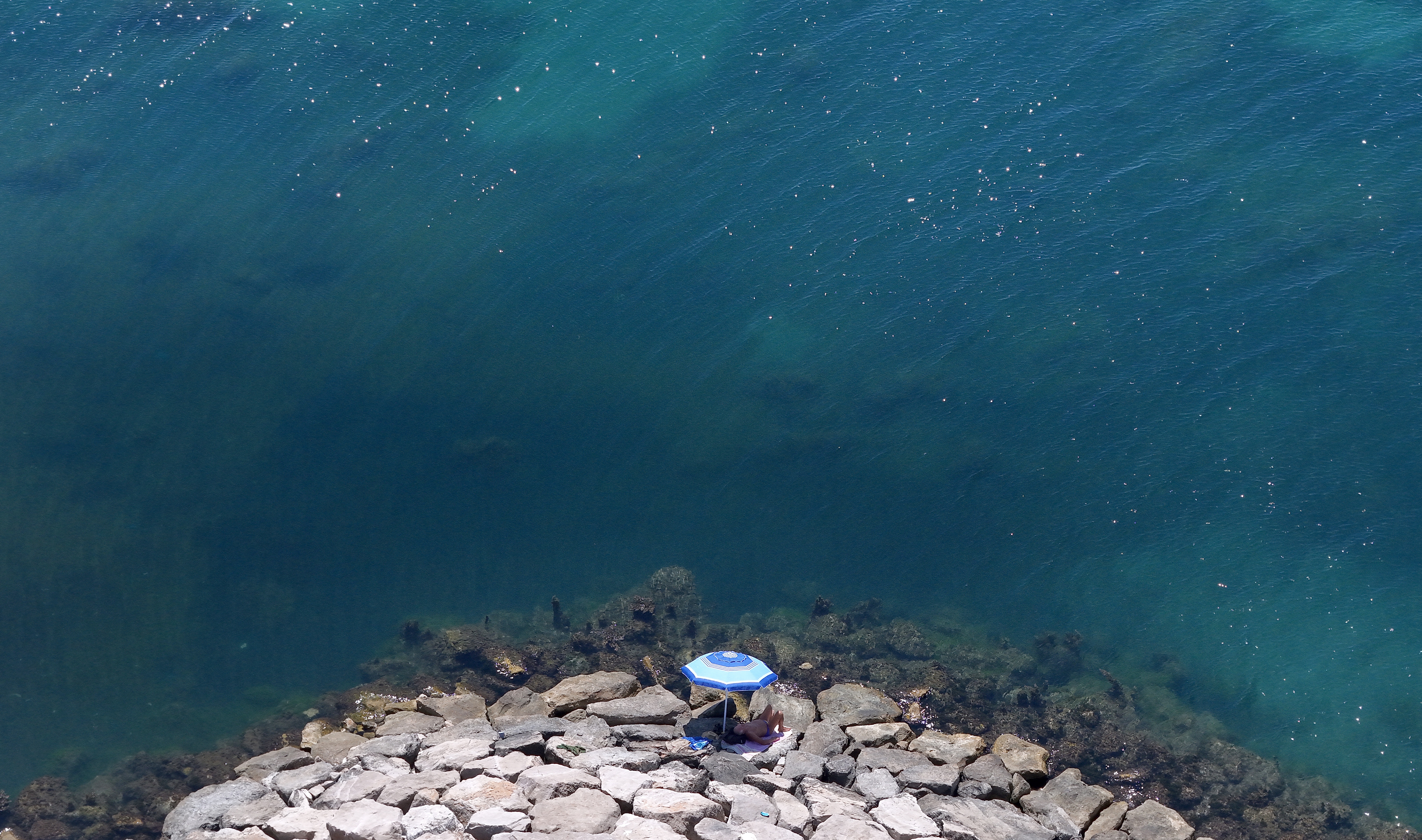 This aerial photograph shows a man sunbathing on rocks in front of the sea in Durres, western Albania, on June 29, 2026.