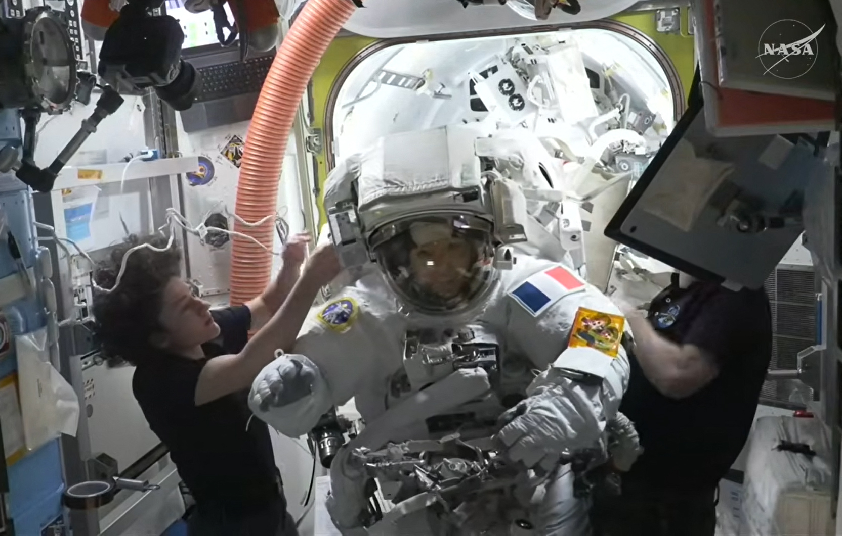 This August 18, 2026, frame grab from a NASA live video stream shows European Space Agency (ESA) French astronaut Sophie Adenot (C) returning back inside the International Space Station (ISS) after her spacewalk
