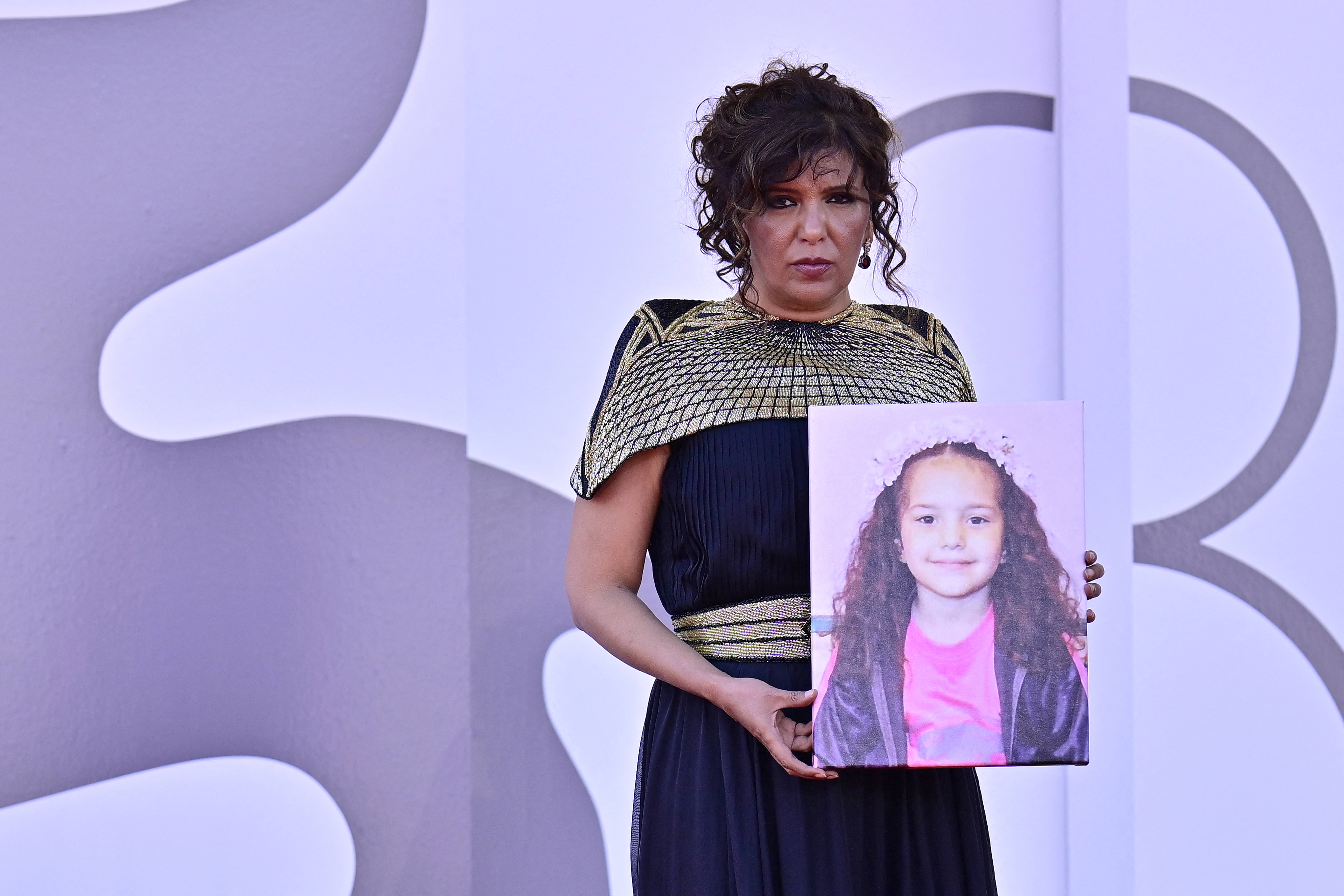 Tunisian director Kaouther Ben Hania holds a portrait of late Palestinian girl Hind Rajab, during the red carpet for the movie "The Voice of Hind Rajab"