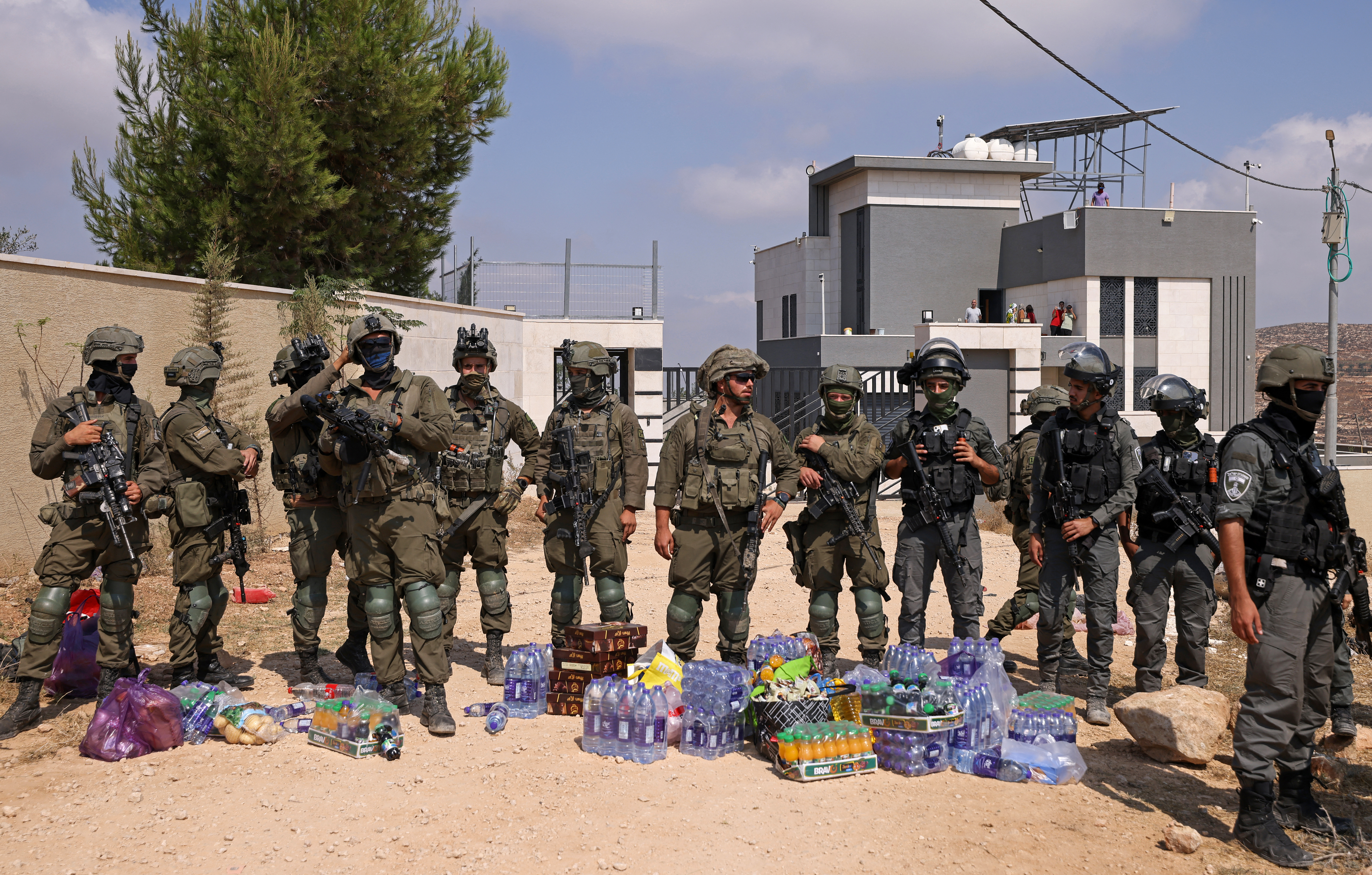 Israeli soldiers stand in front of the entrance of a besieged Palestinian house by Israeli settlers in the village of Qusra, south of Nablus, in the occupied West Bank, on August 14, 2026