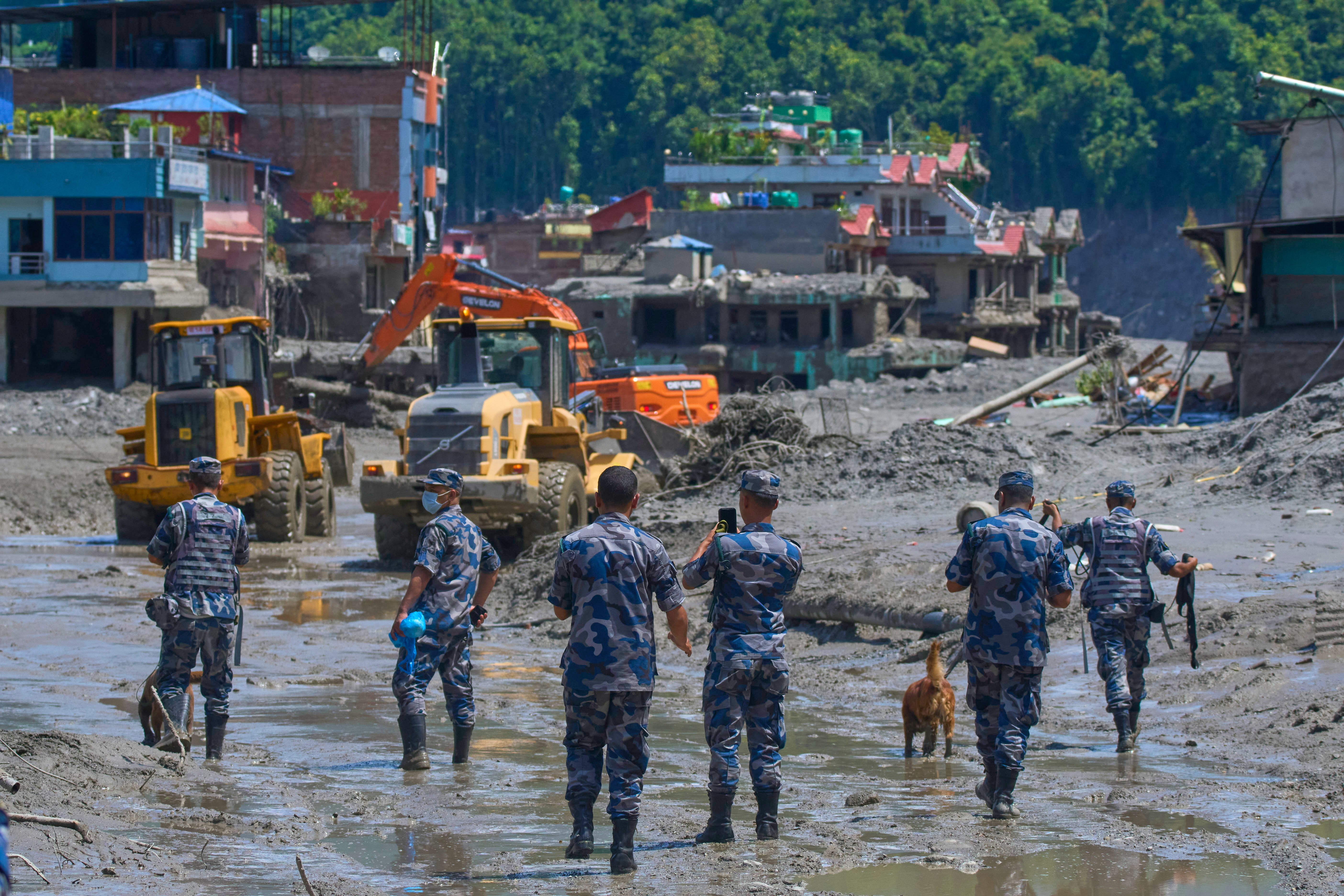Nepalese policemen watch as earthmovers clear the debris of flash flooding. (AP Photo/Niranjan Shrestha)