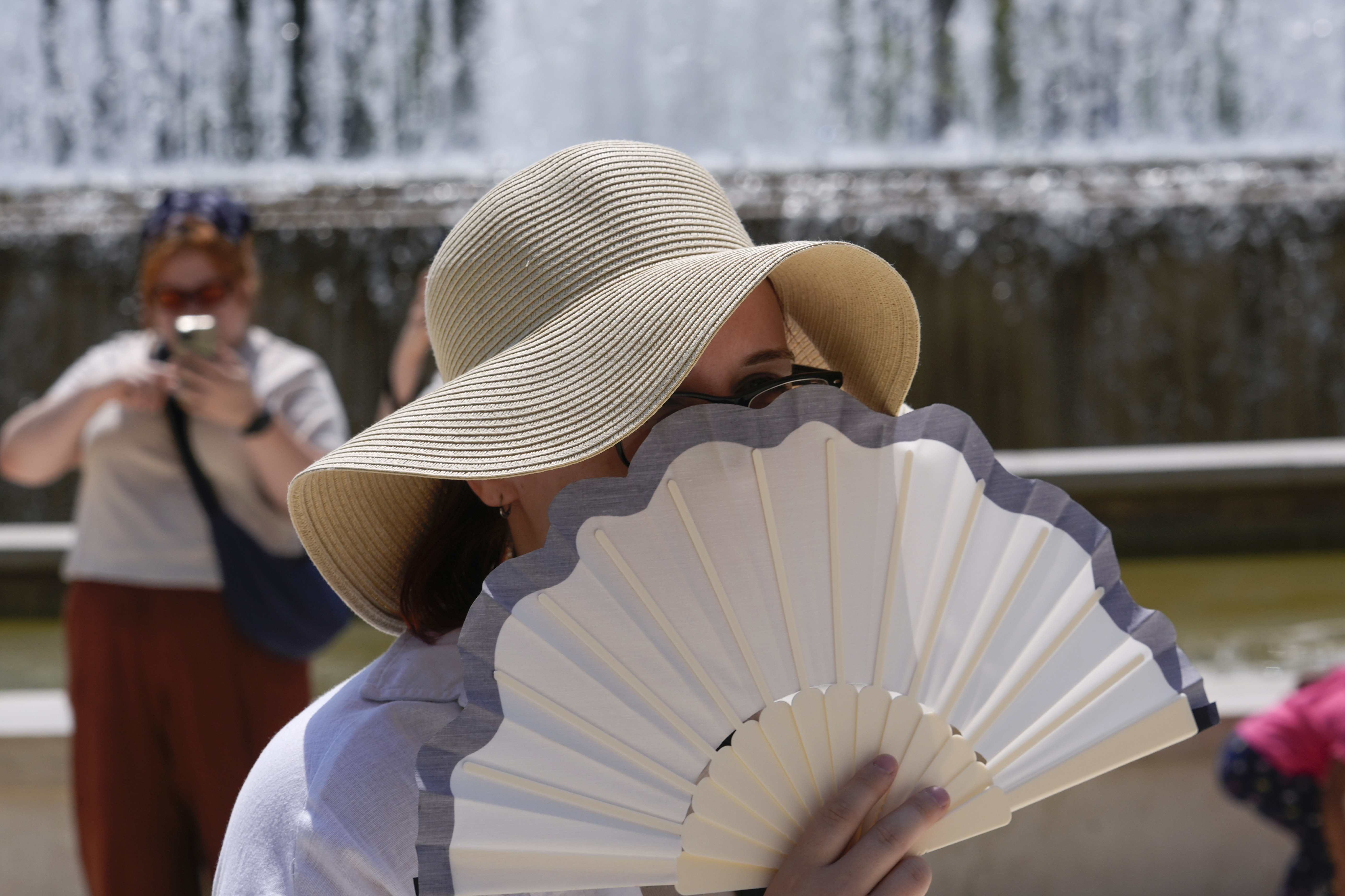 A tourist shelters from the sun by a fountain in front of the Sforzesco Castle in Milan, Italy, July 11, 2024. (AP Photo/Luca Bruno, File)