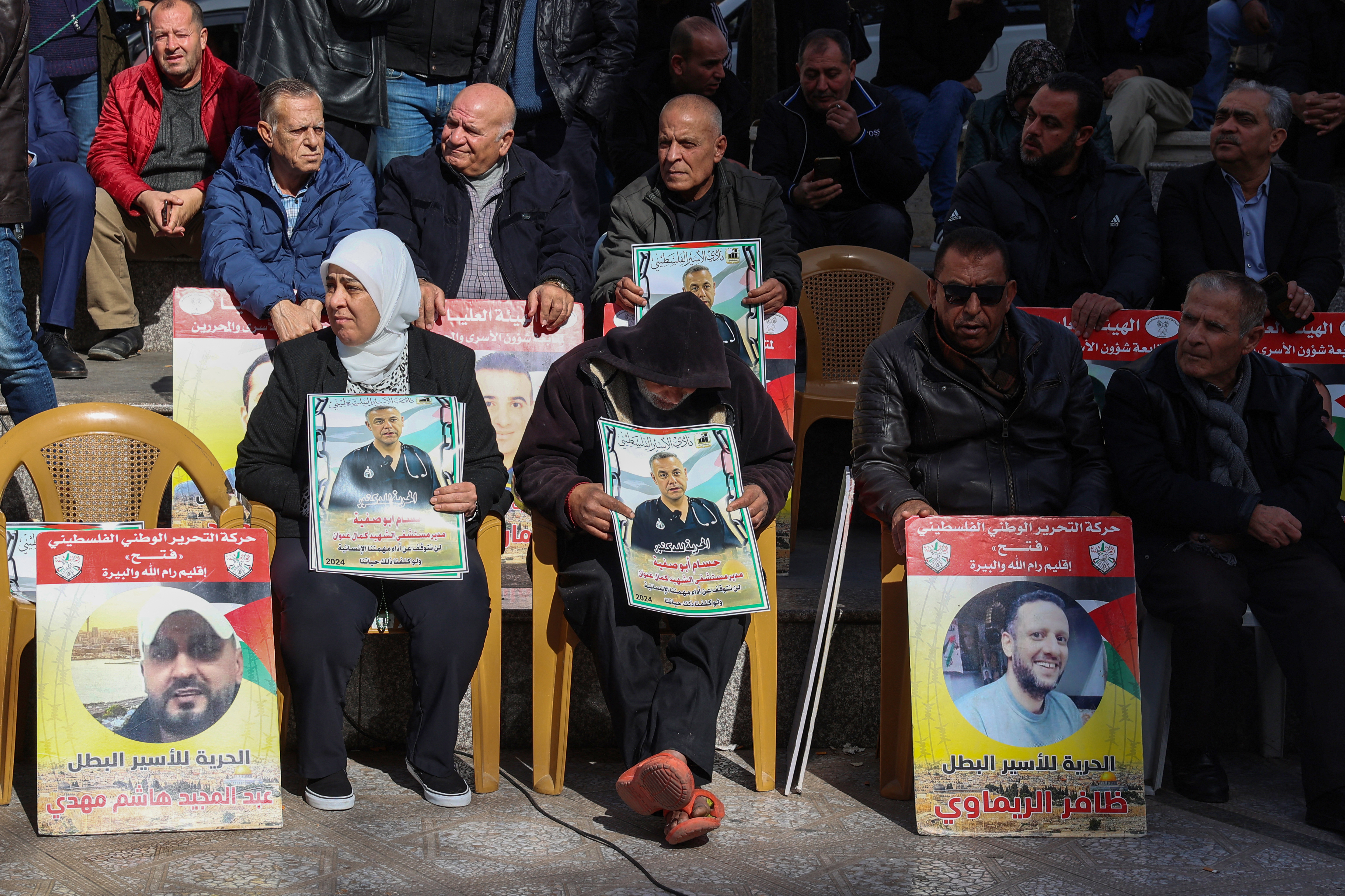 People lift placards bearing portraits of Palestinians currently detained by Israel, including the director of the Kamal Adwan Hospital in Gaza Hussam Abu Safiya