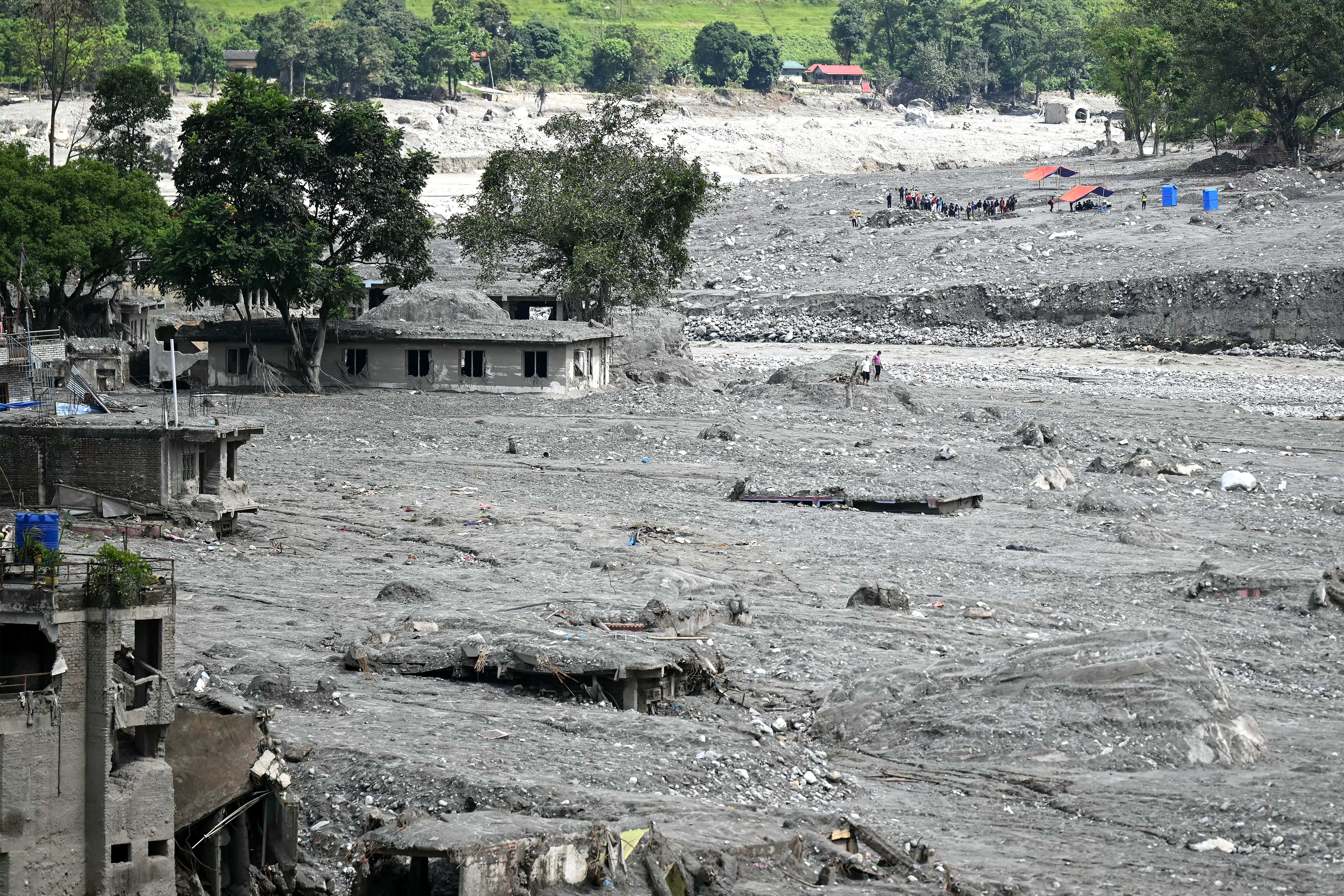 People walk amidst damaged houses in the aftermath of flash floods at Trishuli in Nepal's Nuwakot district on September 11, 2026. (Photo by PRAKASH MATHEMA / AFP)