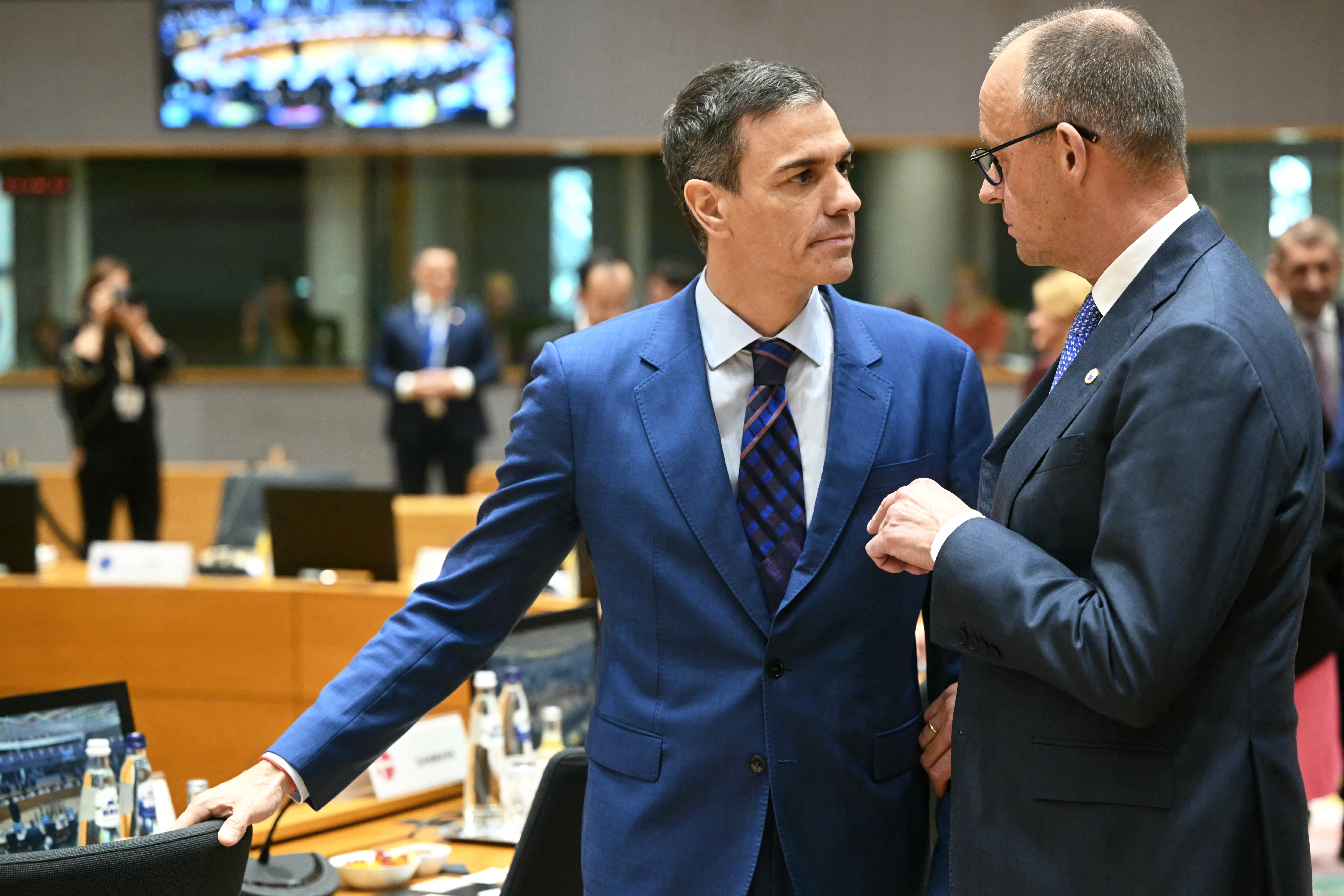 Spain's Prime Minister Pedro Sanchez speaks with Germany's Chancellor Friedrich Merz (R) ahead of rountable during the EU Summit at the EU headquarters in Brusselsl