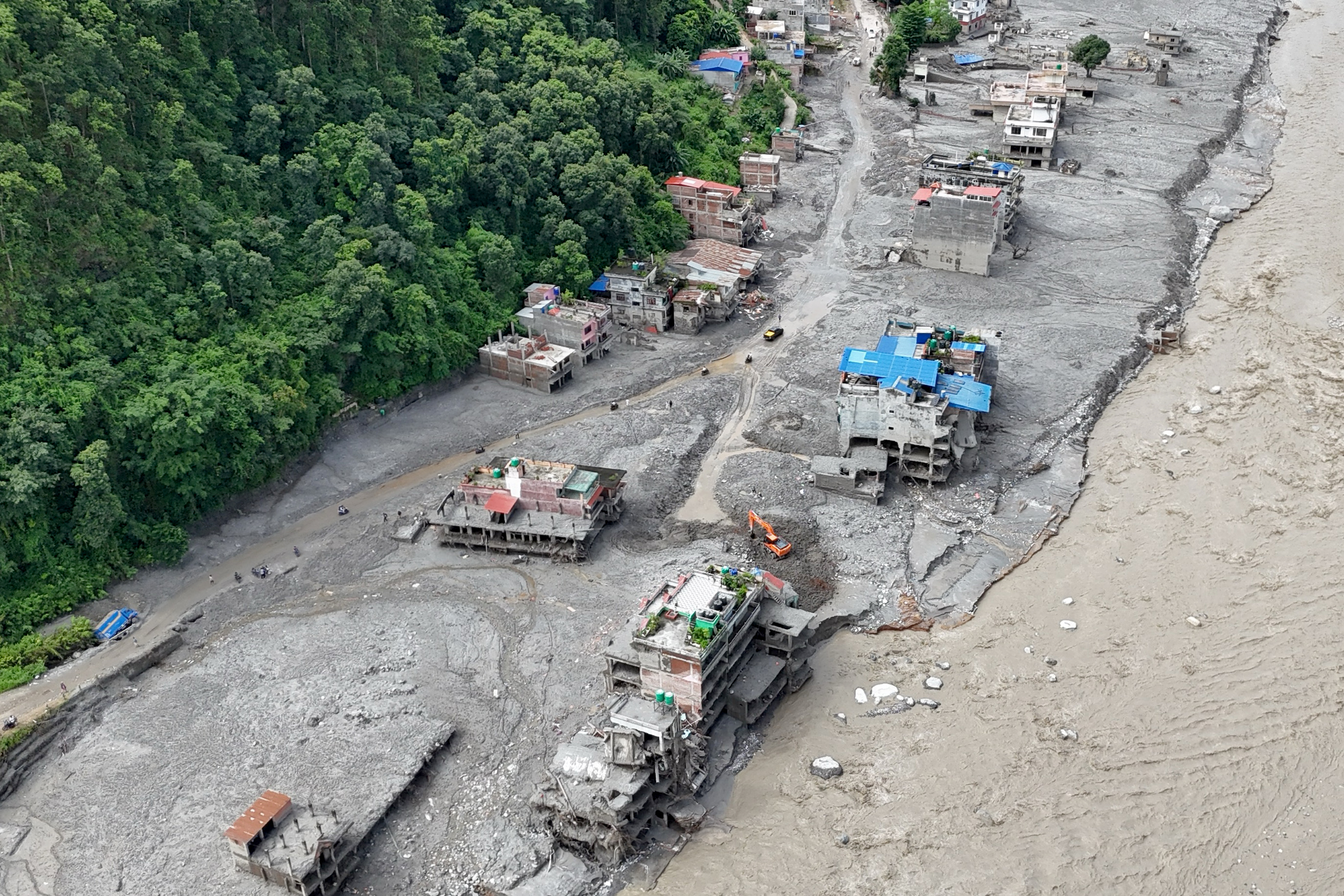 An aerial view shows a torrent of muddy water surging past houses and through the Trishuli River in the aftermath of flash floods at Trishuli Center in Nepal's Nuwakot district on September 1, 2026.