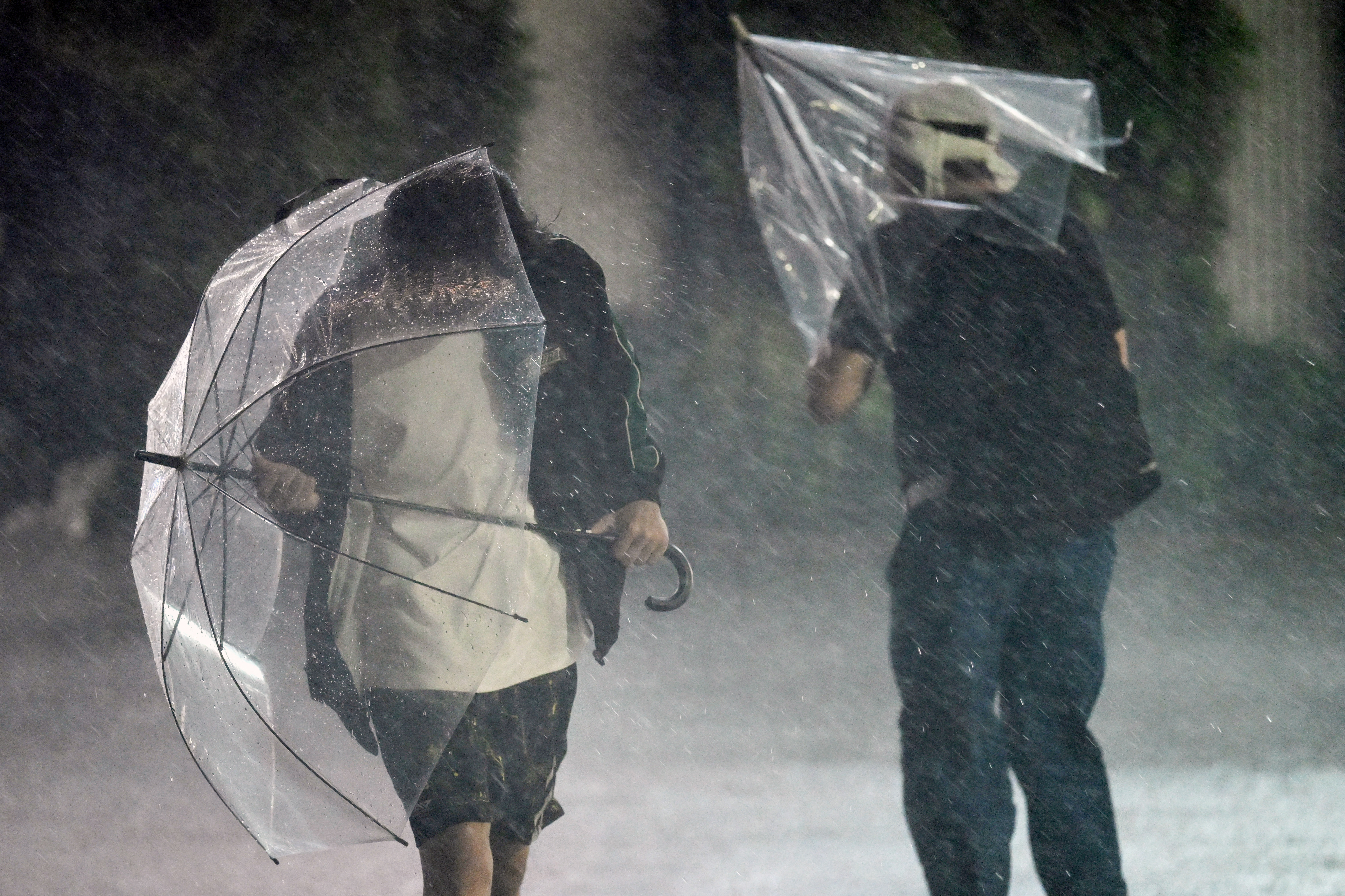 Pedestrians hold on to their umbrellas amid strong winds and heavy rainfall. (Photo by Rie KIKUCHI / AFP)