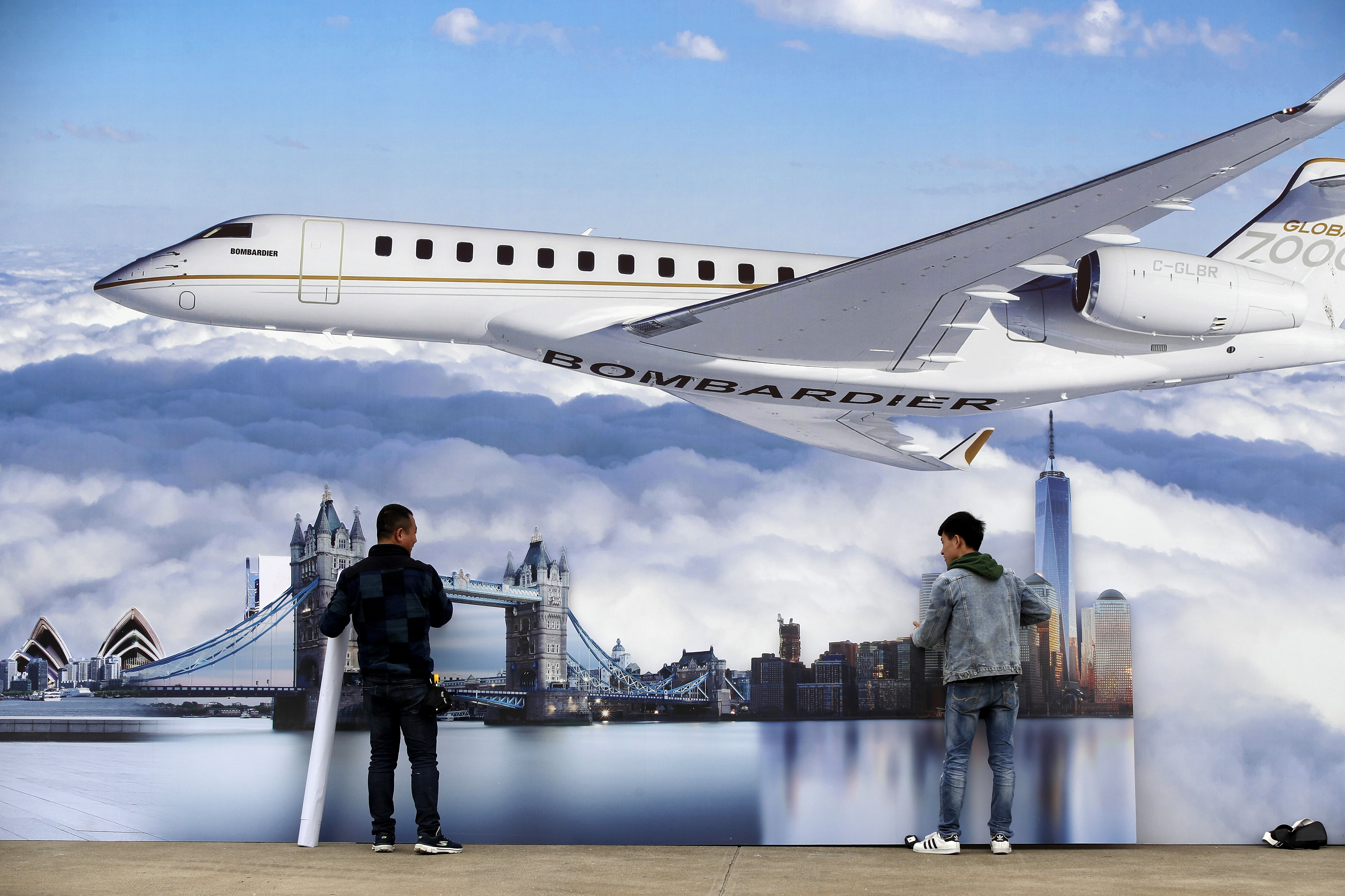 Workers prepare scenics posters against the Canada's Bombardier business jet. (AP Photo/Andy Wong)