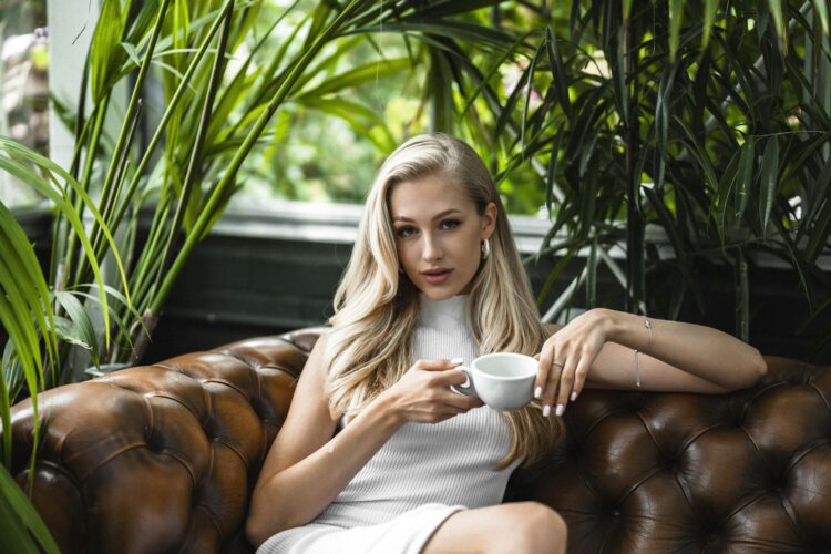 žena pije kavu na kožnom kauču