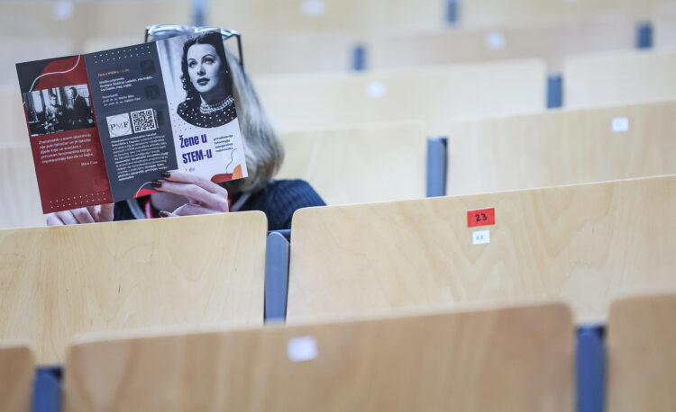 žena drži knjigu "Žene u STEM-u" na konferenciji o ženama u znanosti