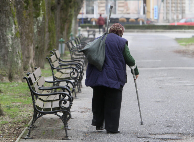 umirovljenica uz pomoć štake hoda parkom