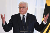 Frank-Walter Steinmeier u crnom odijelu za govornicom s podignutim rukama