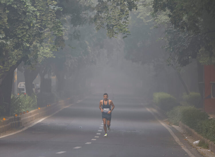 Indijac trči po cesti dok je oko njega smog i onečišćeni zrak