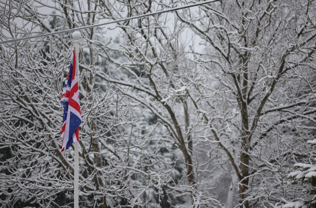 britanska zastava ispred drveća pokrivenog snijegom