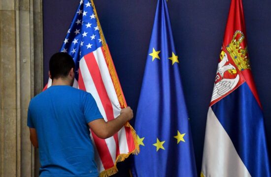 muškarac ispred zastave sad-a, pored nje zastave europske unije i srbije