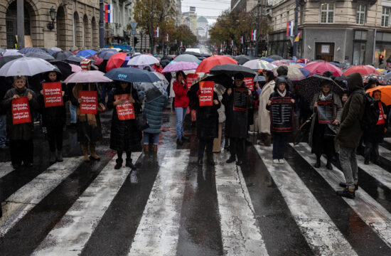 prosvjed Beograd, ljudi pod kišobranima sa crvenim transparentima u rukama