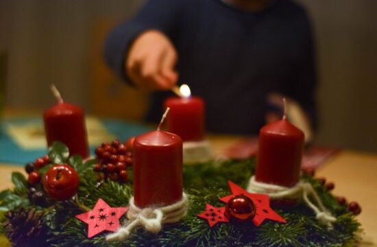 Osoba pali šrvu adventsku svijeću na vijencu.