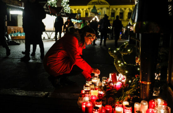 žena čuči pored hrpe upaljenih lampaša u magdeburgu