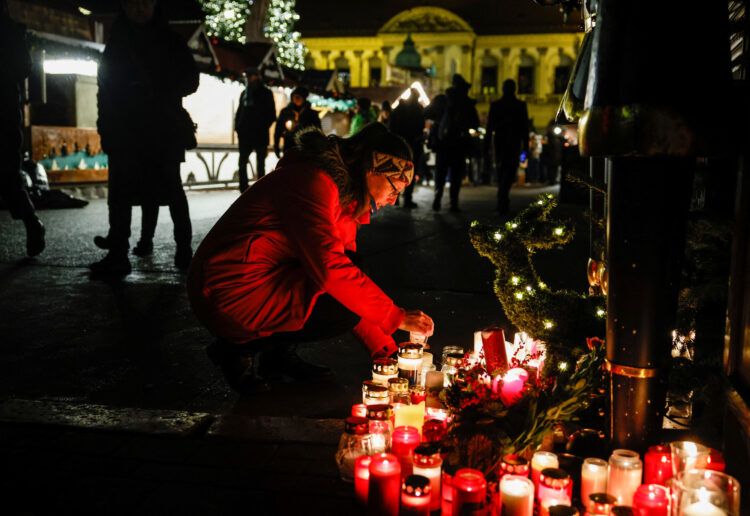 žena čuči pored hrpe upaljenih lampaša u magdeburgu